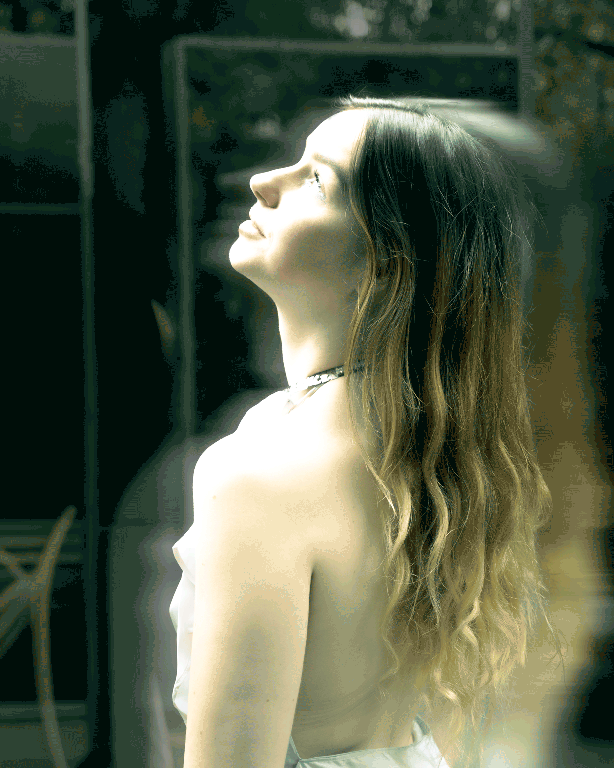 A woman with long wavy hair looking upward with a serene expression.