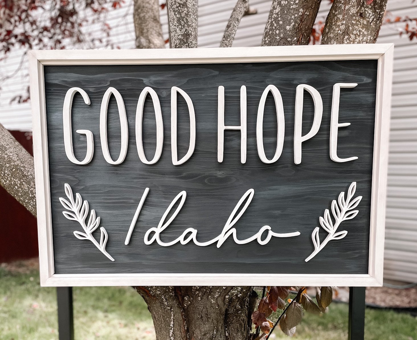 A decorative outdoor sign reading 'Good Hope Idaho' with white lettering and leaf accents.