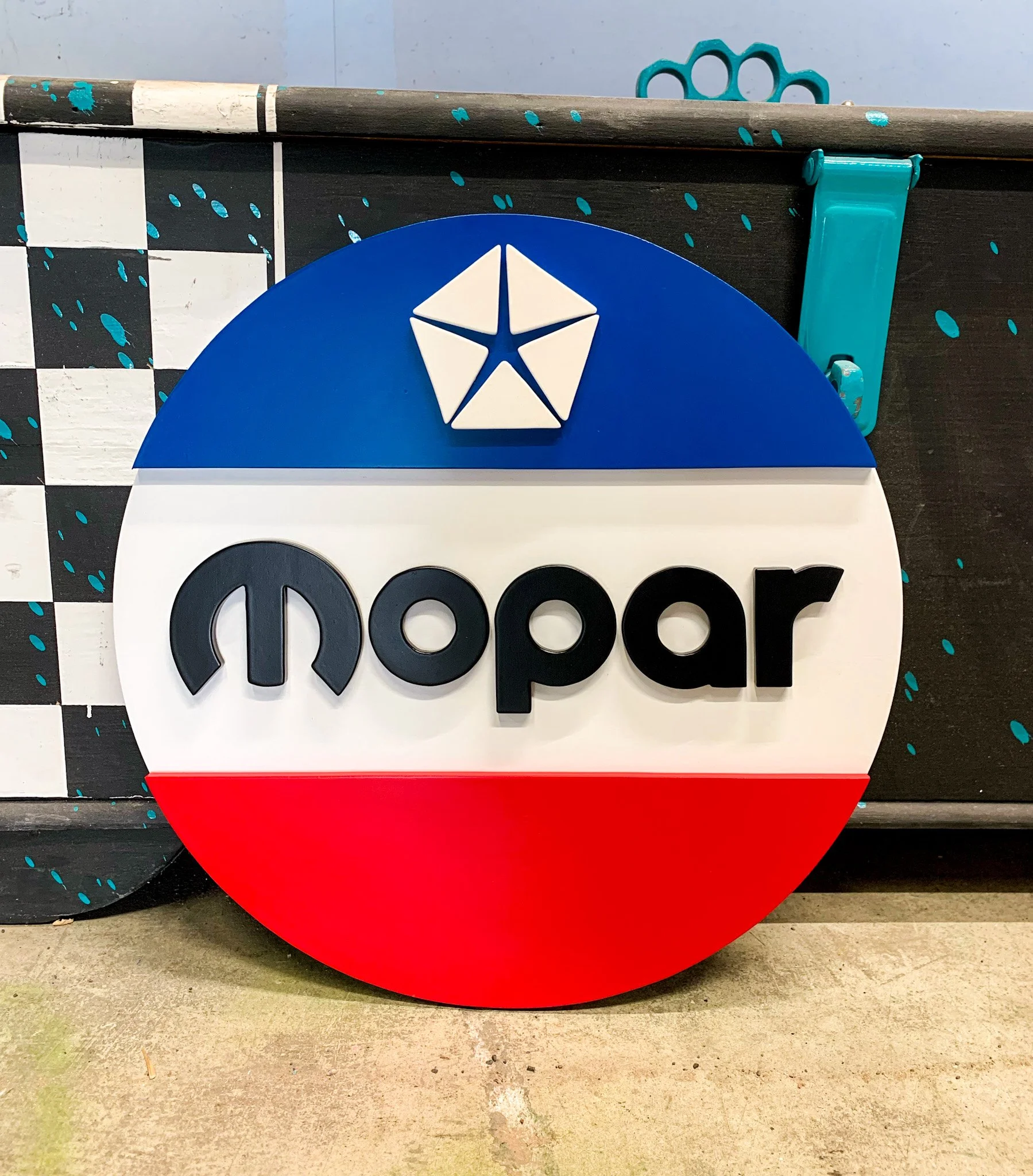 A division logo with blue, white, and red colors, featuring the Chrysler pentastar emblem on top and the word 'mopar' underneath in black letters.