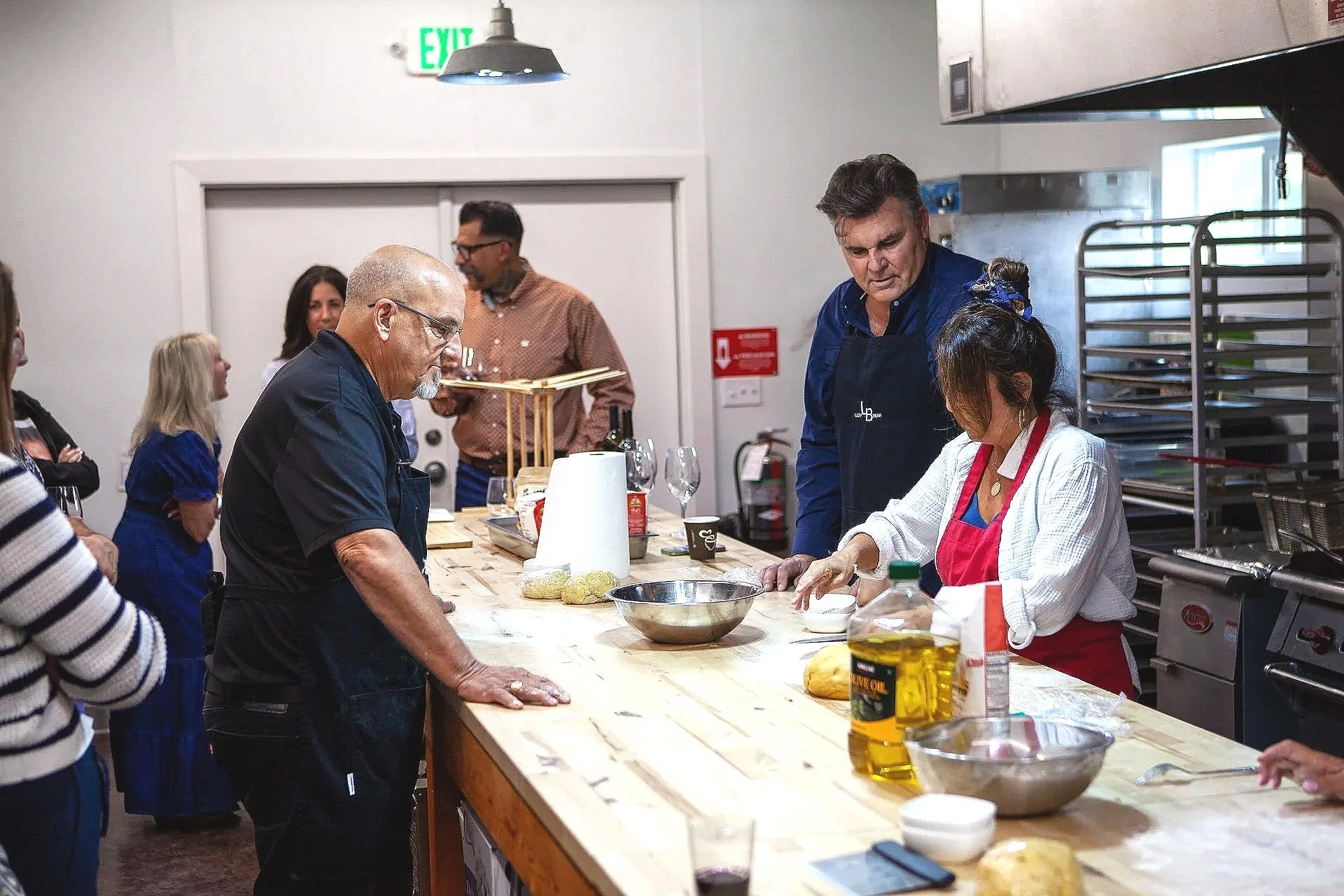 People gathered around a kitchen counter participating in a cooking class or demonstration.