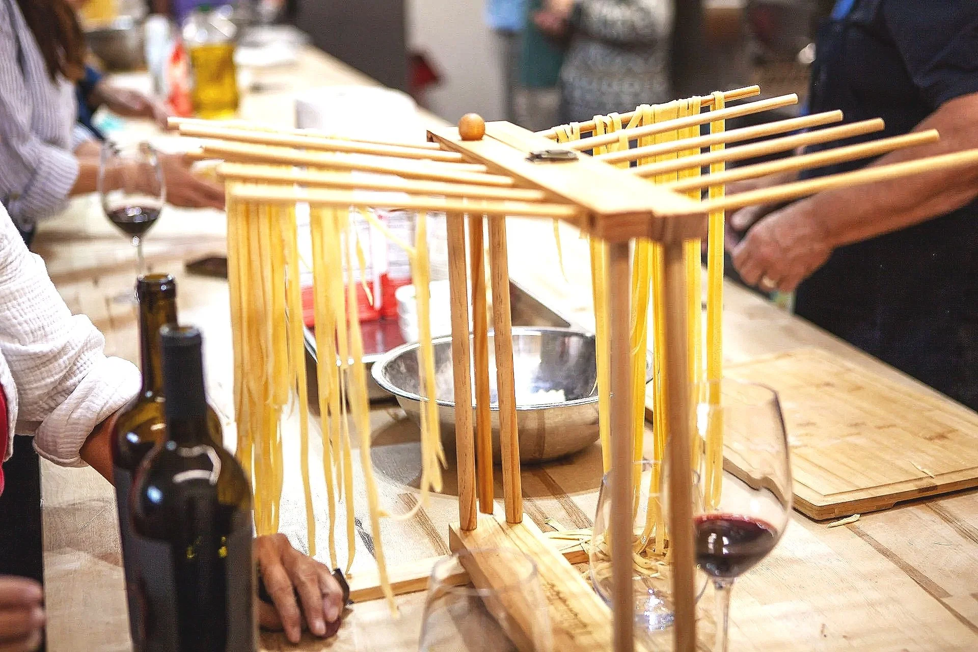 Spaghetti noodles hanging on wooden racks in a kitchen or restaurant setting.