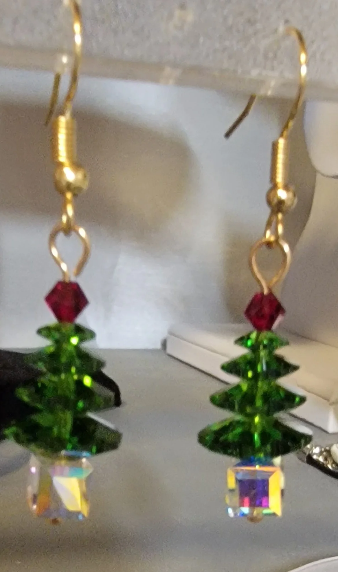 Festive earrings shaped like Christmas trees with green beads, red accents, and iridescent cube bases