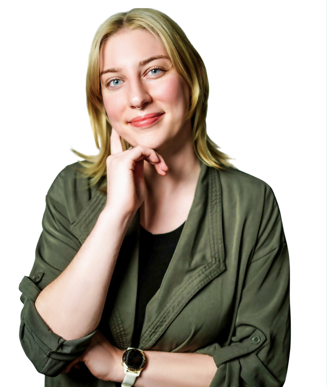 A woman with blonde hair and blue eyes smiling, wearing a black top, olive green jacket, and a white watch, resting her chin on her hand.