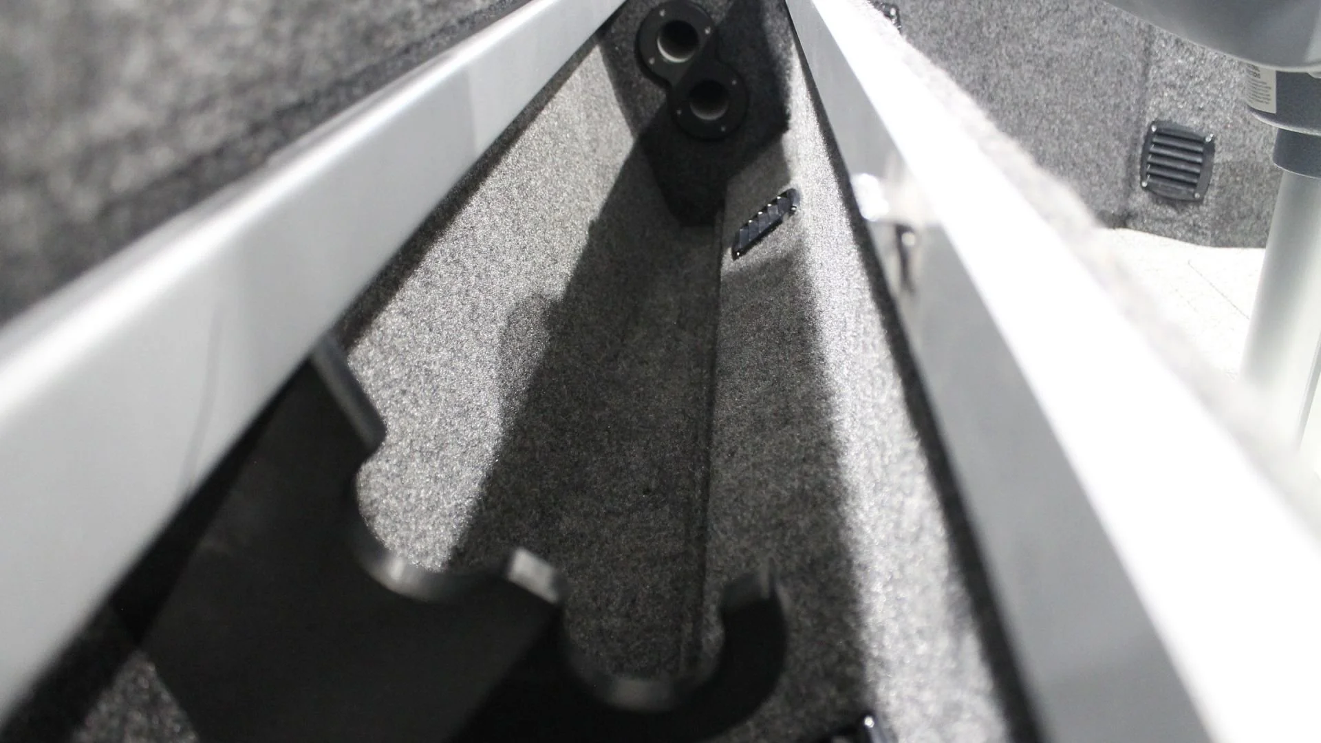 The interior of a storage compartment with foam padding, two circular openings, and a small electronic component.