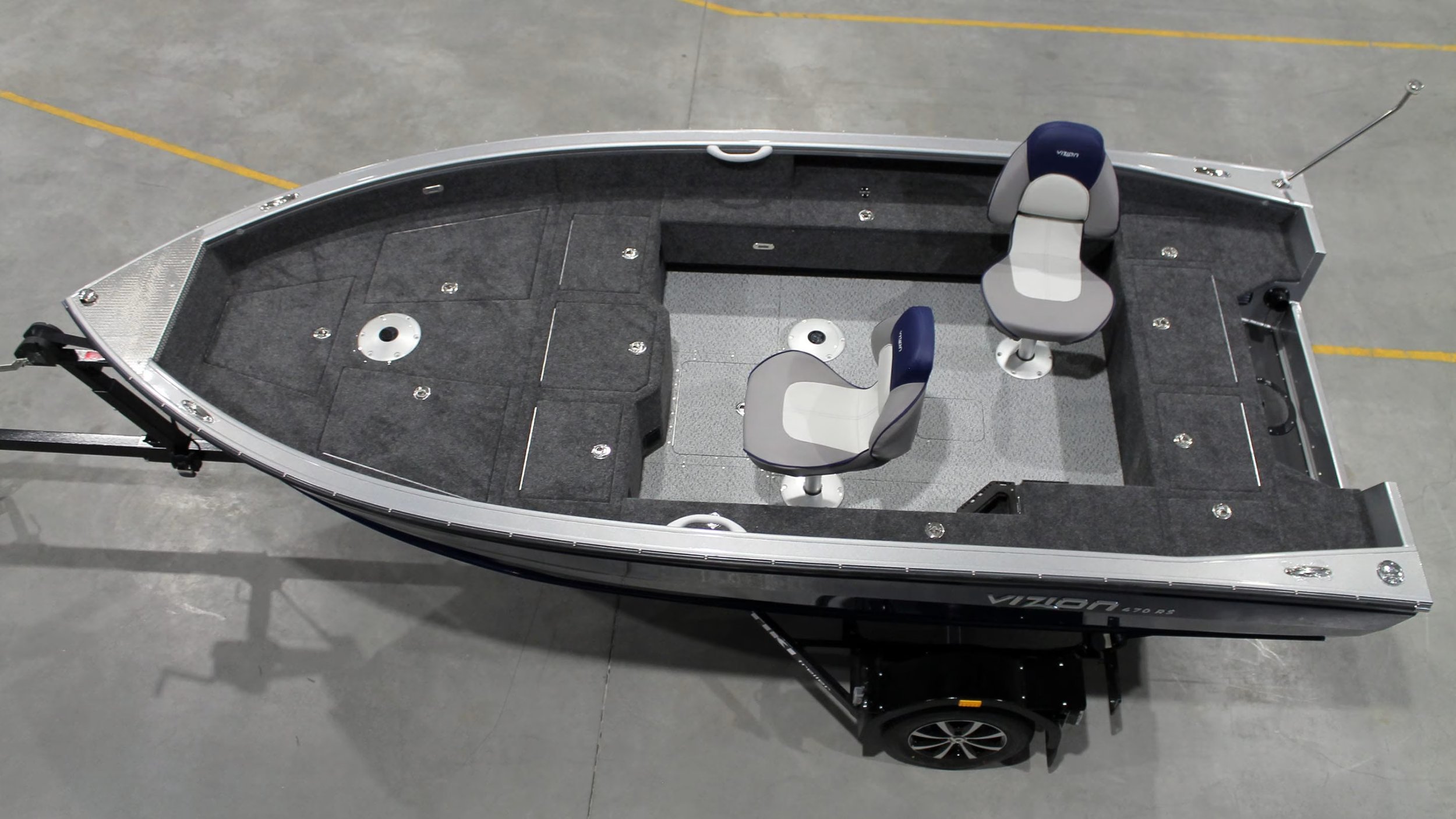 Top view of a boat with two chairs inside, sitting on a trailer in a warehouse