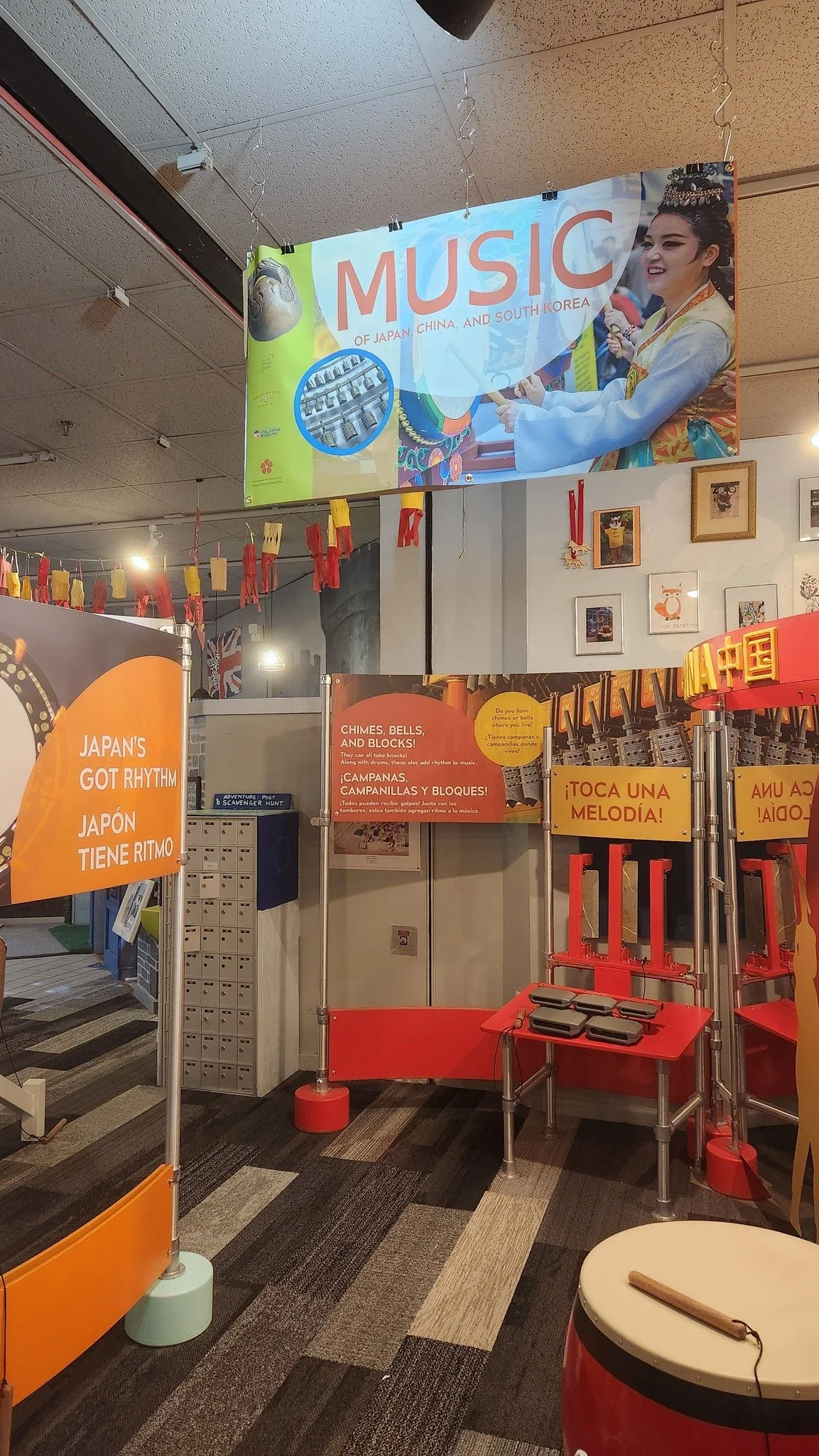 An indoor exhibit space for the Music of Asia exhibit, with stations for each type of drum and signage describing how to play.