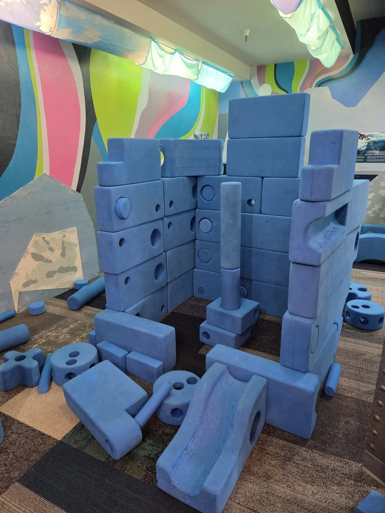 A structure made from giant blue foam blocks. The structure resembles an igloo-like shape, as the blue blocks are in the North/South Pole exhibit.