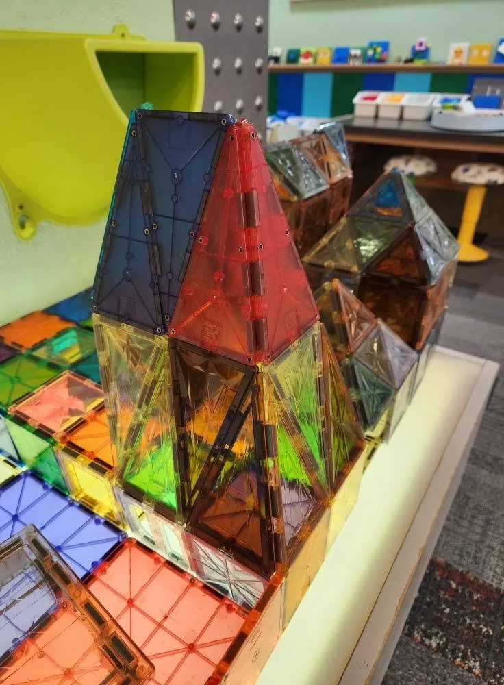 Magnetic tiles arranged to look like a castle on top of a light table. The tiles are colorful and lit up from the table.
