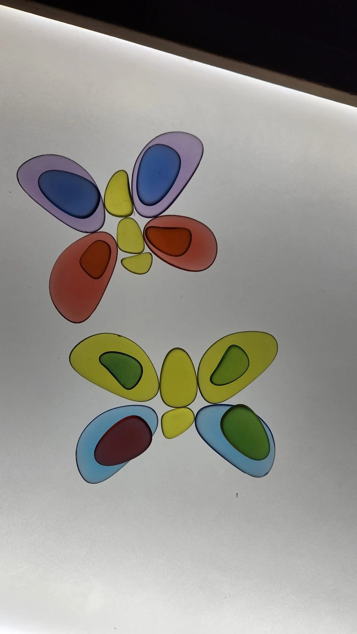 Two butterflies created with glow-in-the-dark rounded tiles, sitting on a light table.