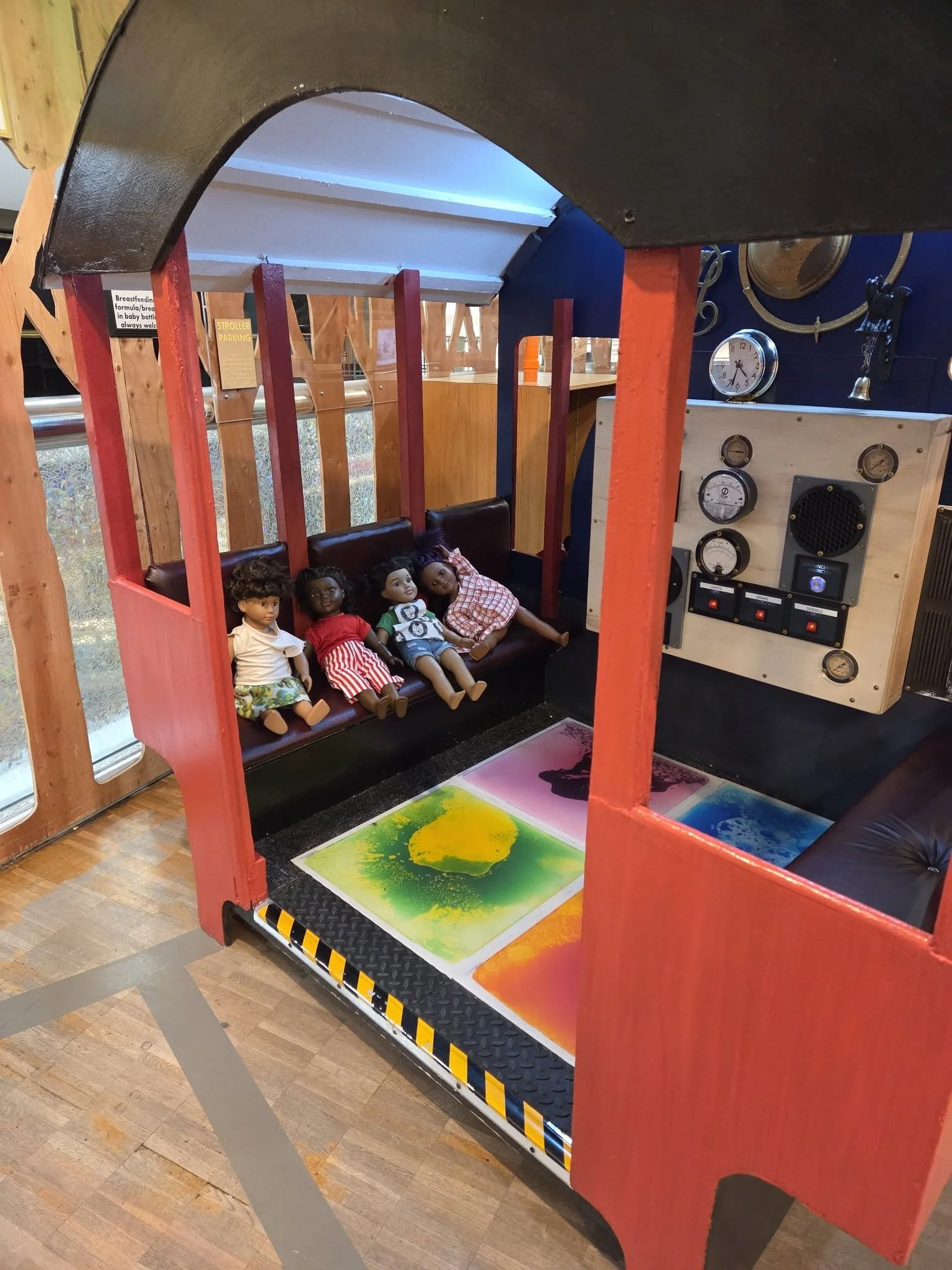 The inside of a train where a conductor might sit. Two benches are on each side, with the floor covered in tile that, when stepped on, creates a slime-like substance that moves. On one of the benches are four dolls, seated as if taking a ride.