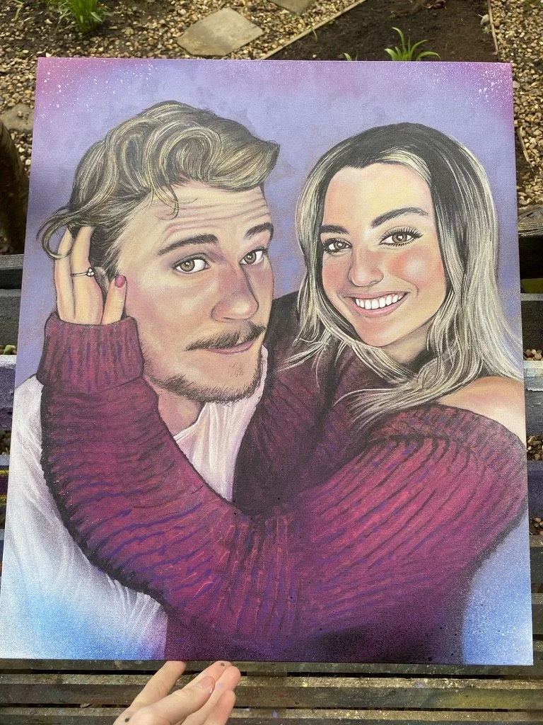 Hand-painted portrait of a smiling man and woman, with the woman embracing the man's shoulders, both wearing sweaters, set against a purple background.