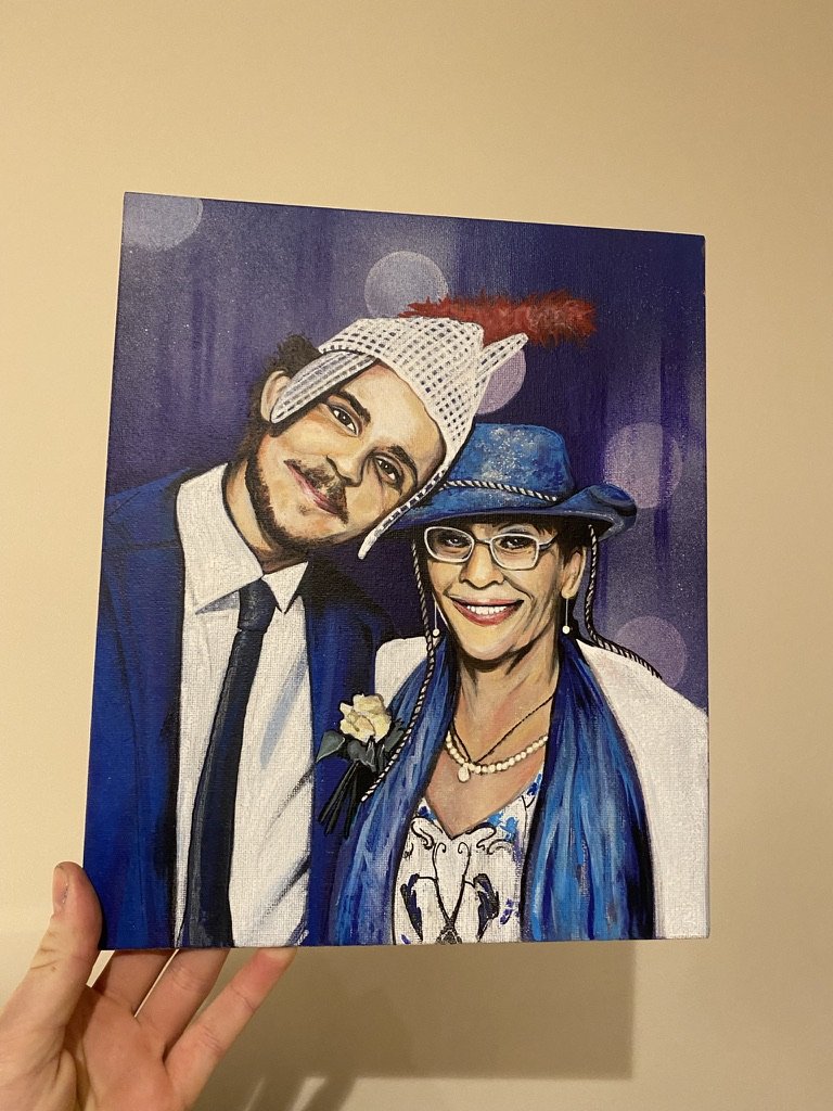 A person holding a digital painting of a man and woman dressed in formal attire with funny hats, smiling against a purple background with bokeh effect.