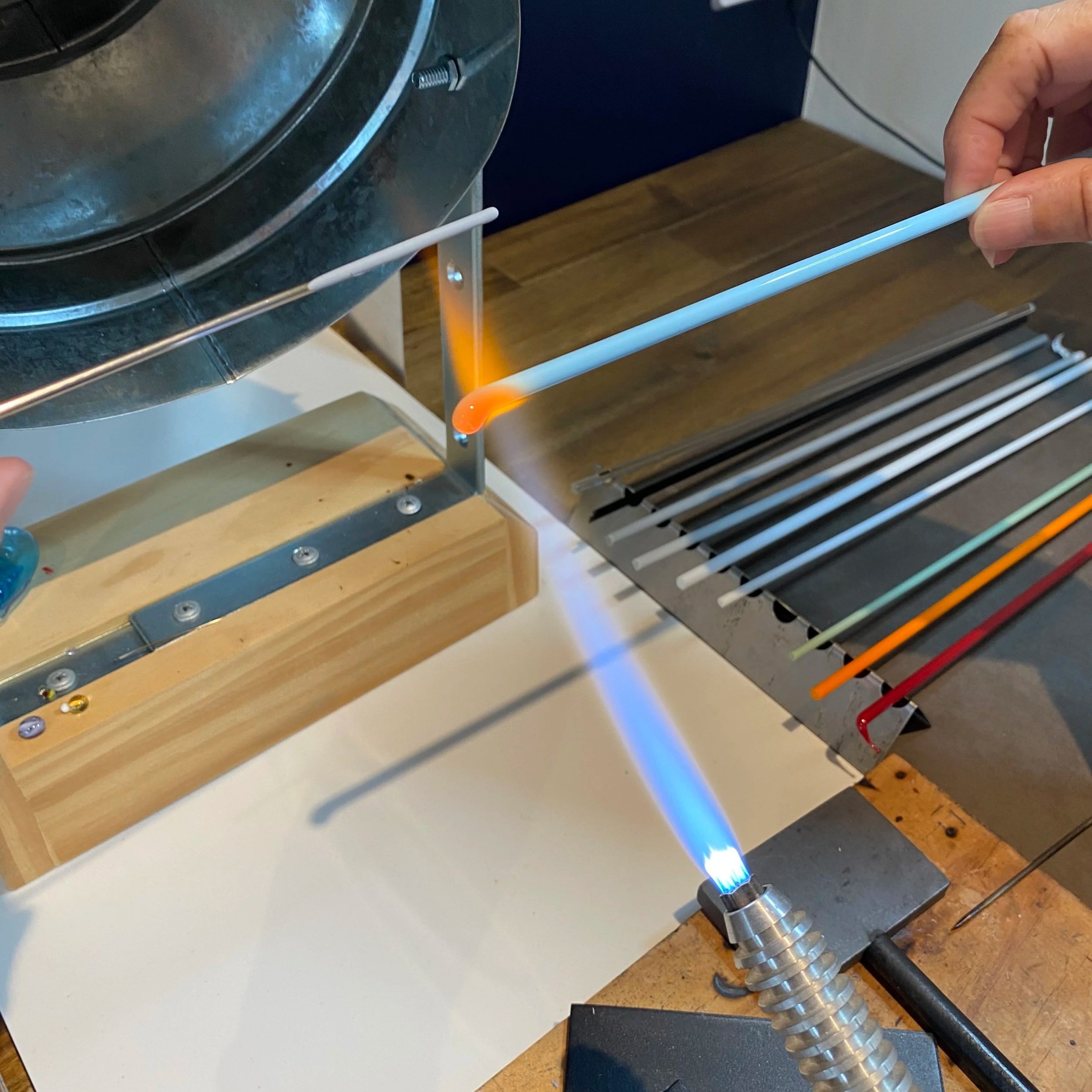 Glass rods being heated with a torch and melted in a lampworking process.