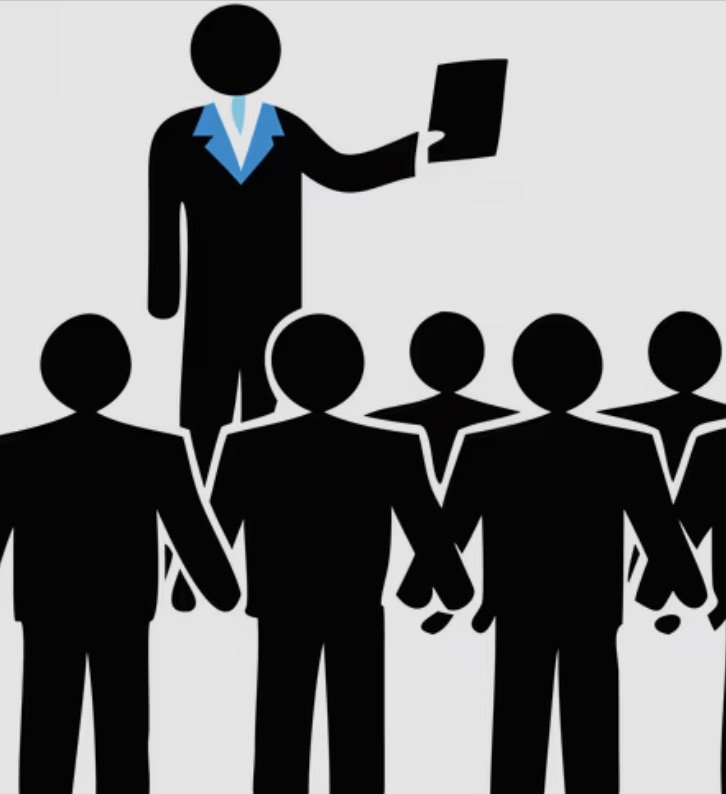 Silhouette of a presenter or speaker standing in front of an audience, holding a tablet or clipboard.