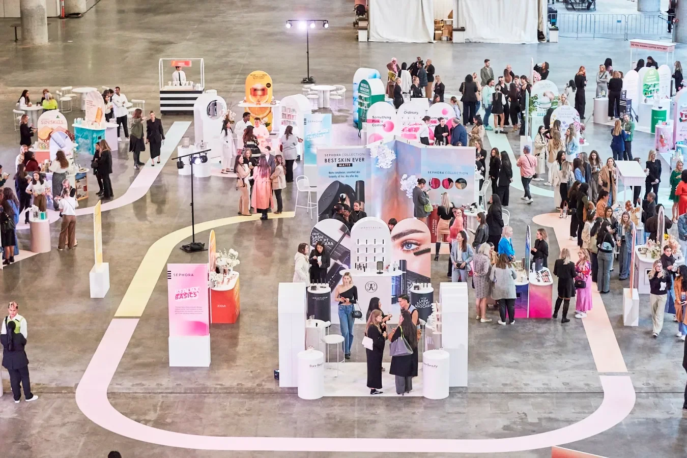 Beauty and skincare expo with multiple booths and banners, attendees browsing and engaging in conversations in a large indoor space.