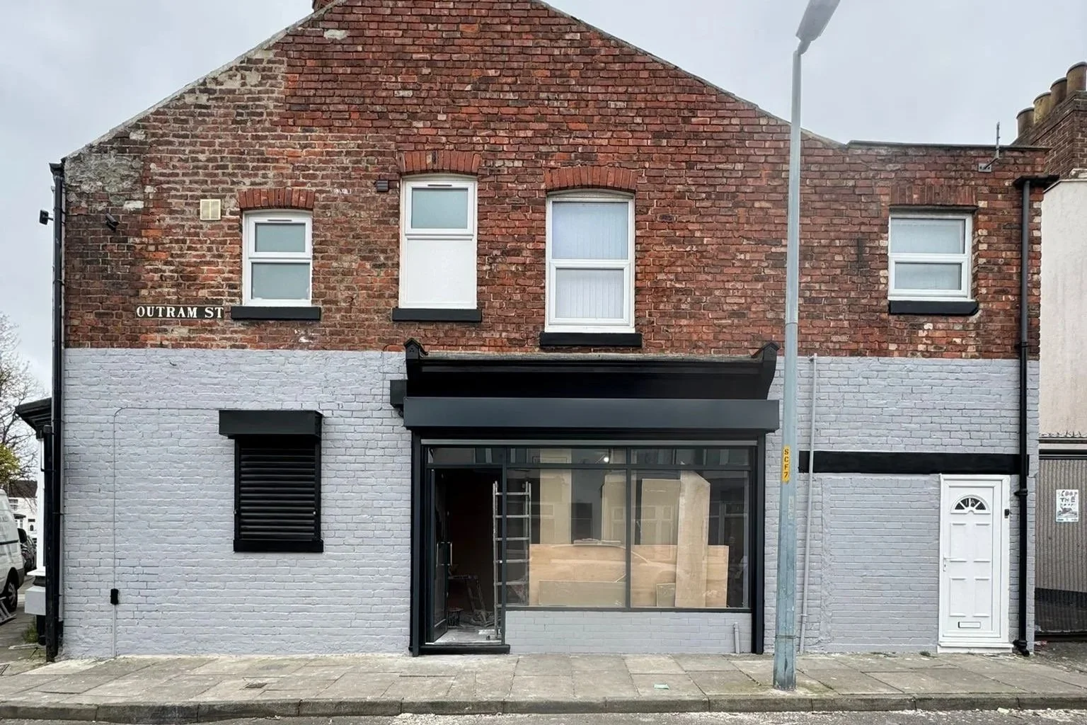 Commercial property exterior after repainting with grey brickwork and modern black storefront.