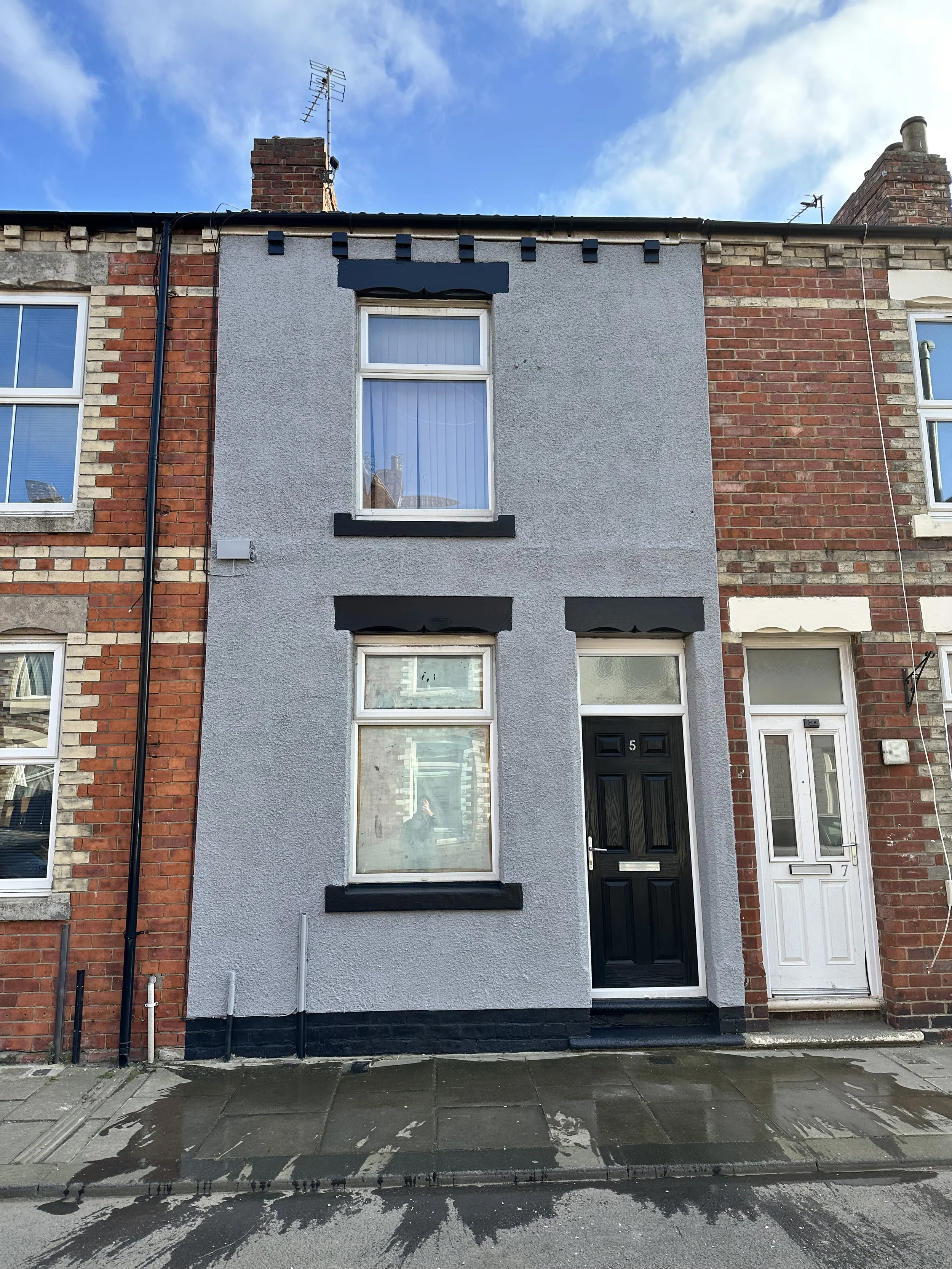 Newly painted terraced house with grey exterior walls and black door and window trim