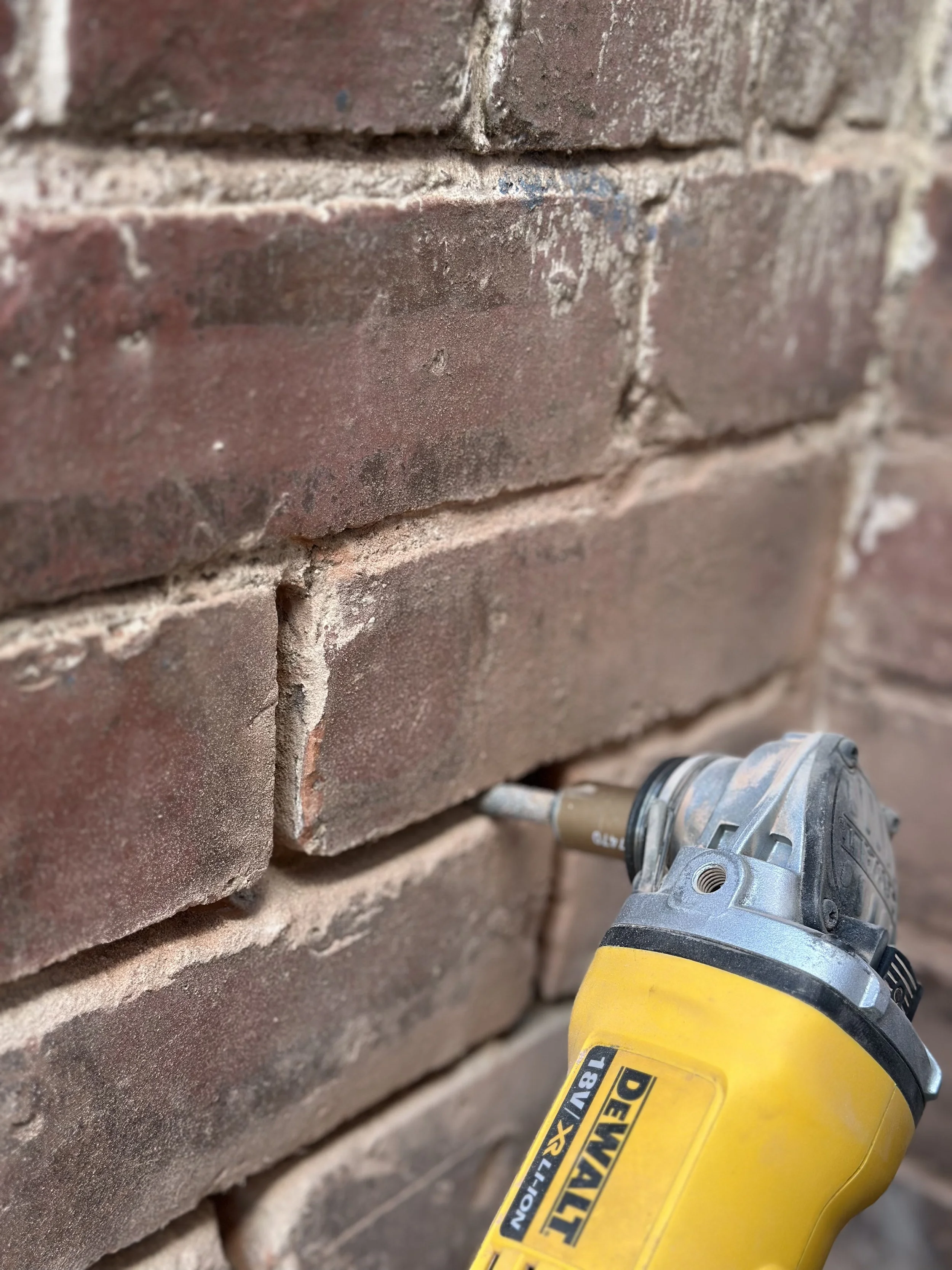 Close-up of a DeWalt impact driver drilling into a red brick wall for masonry work