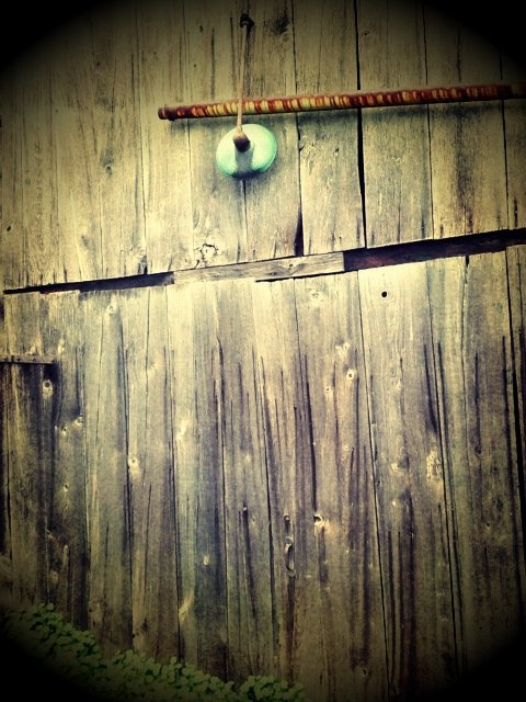 A wooden fence with a pole and a hanging small green and white object.