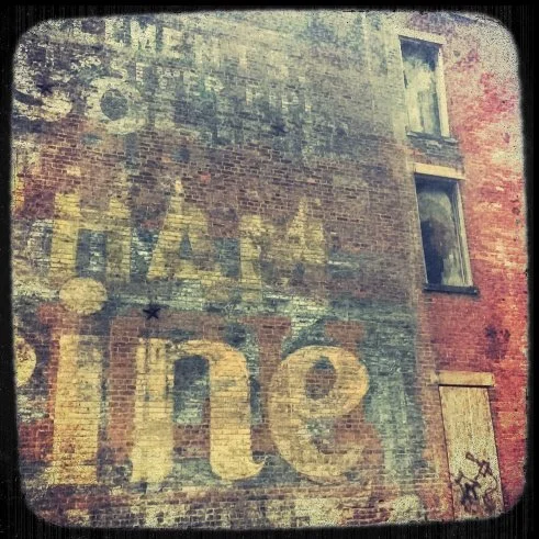 Faded vintage advertisement painted on a brick wall, featuring the words 'the letter of the law' and 'innocent' in large letters with additional faded text.