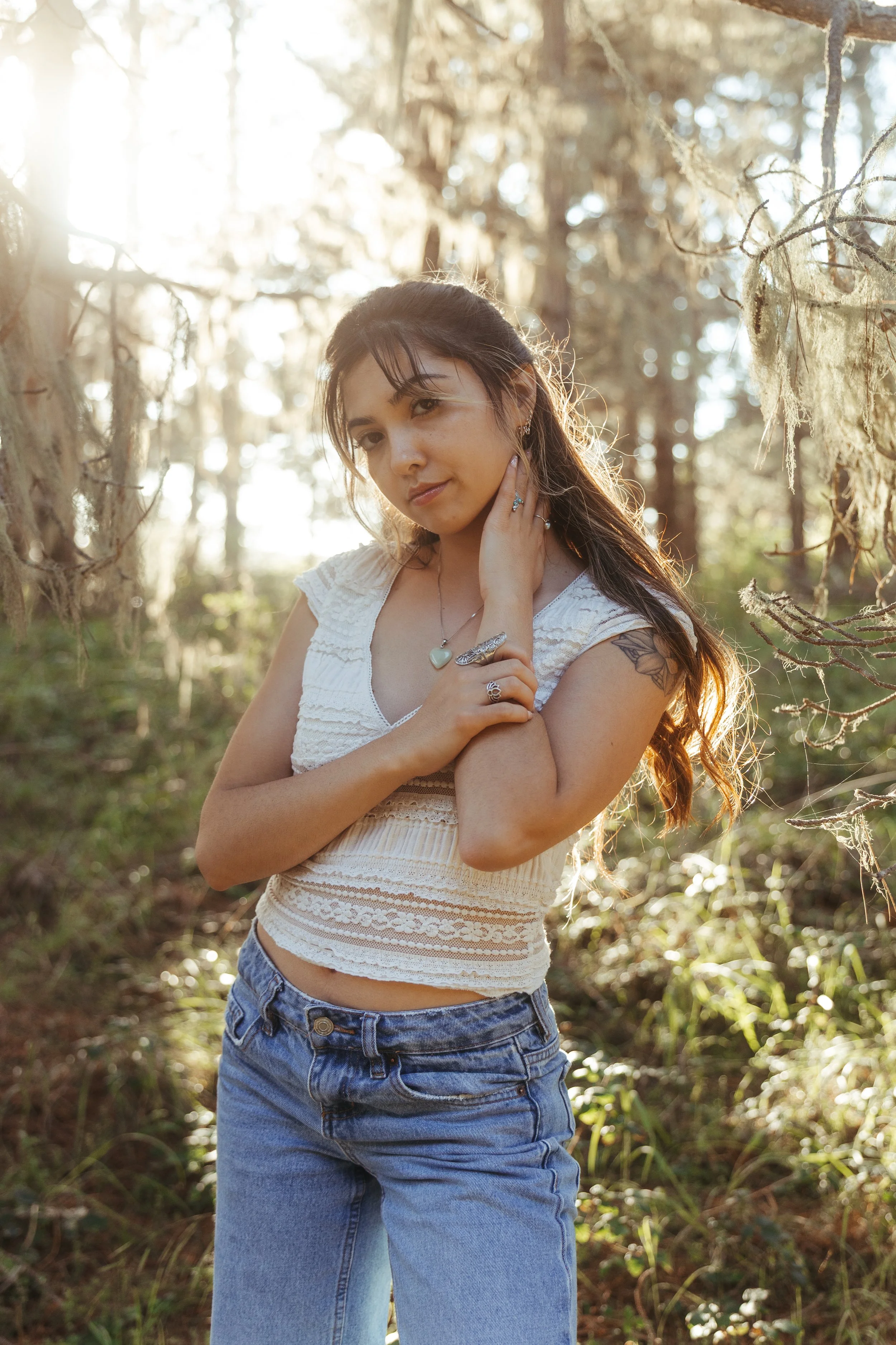 young woman in a forest with a glowing sunset behind her, coastal preserve off the coast of California near Monterey Bay