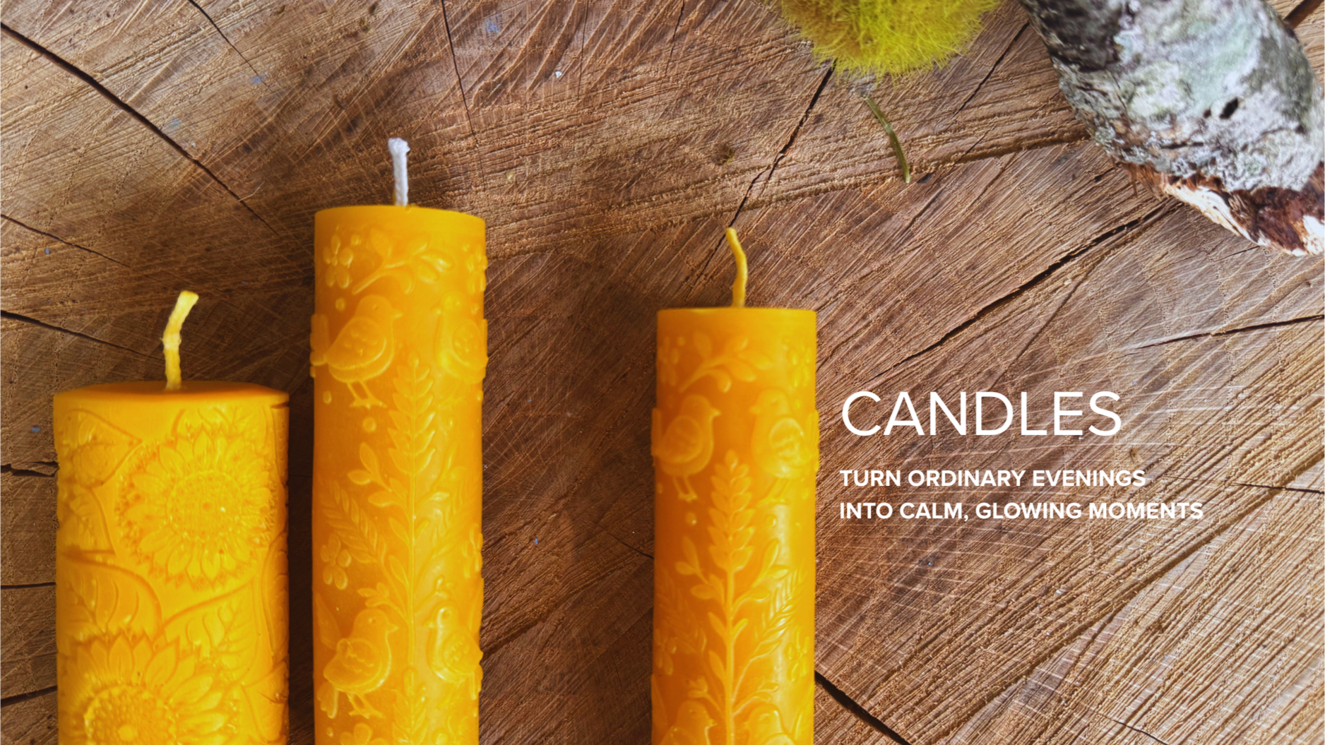 Three yellow candles with intricate floral and bird patterns on a wooden surface. The caption reads 'CANDLES: Turn ordinary evenings into calm, glowing moments.'