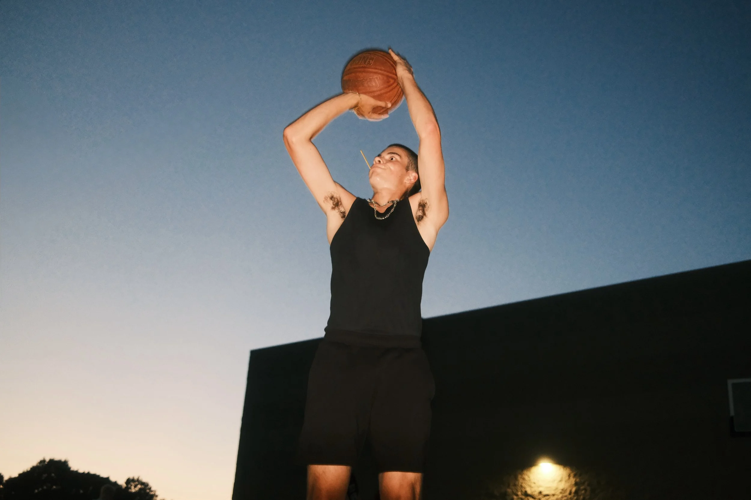 Person in black athletic clothing about to shoot a basketball.