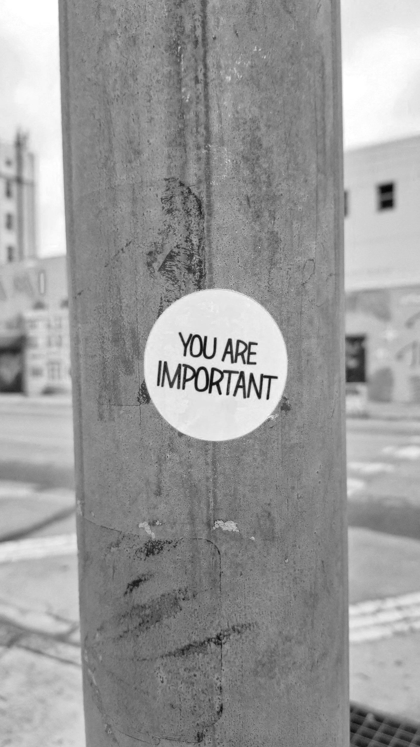 A round sticker on a utility pole that says "You are important" in black text. The background shows a street scene with buildings.