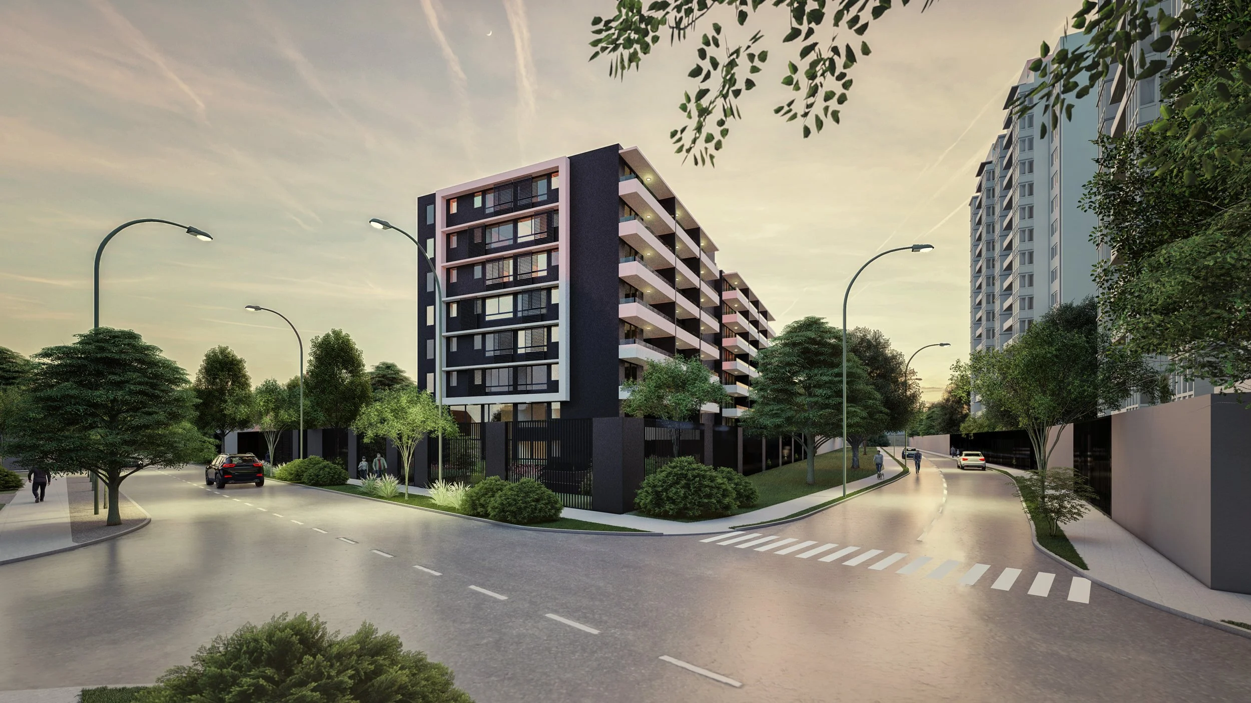 A modern residential building with multiple floors, balconies, and a dark exterior, situated on a city street corner with green trees, streetlights, and cars parked along the road at sunset.