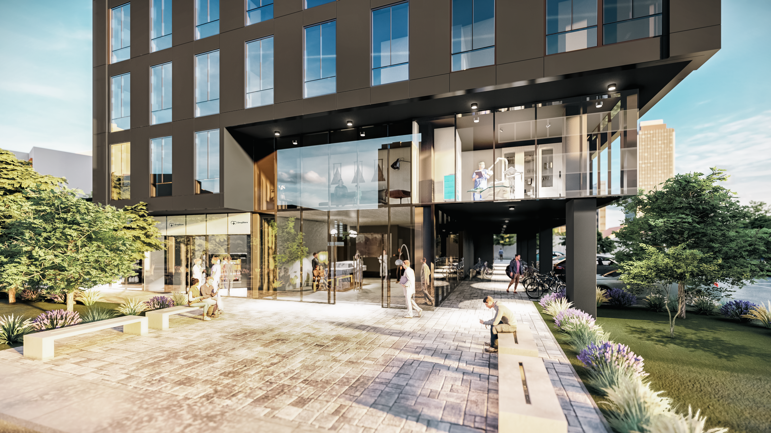 Modern multi-story building with large glass windows and an outdoor seating area, surrounded by trees and landscaped greenery