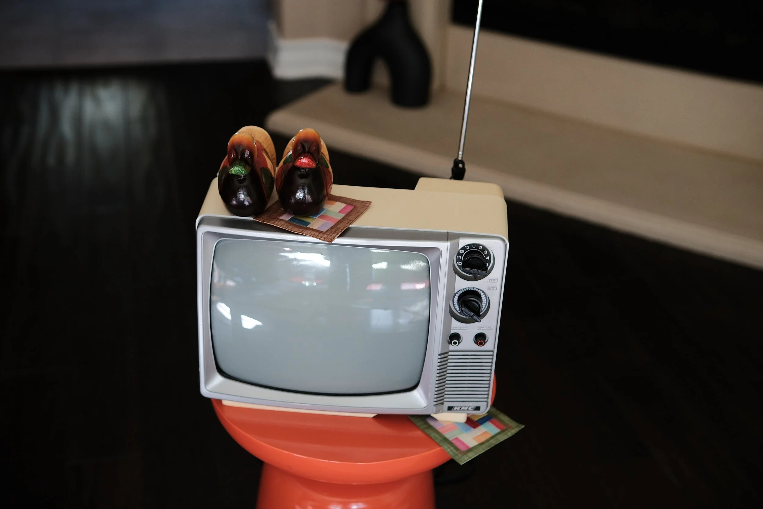 Vintage CRT television with rabbit figurines on top, displayed on a red stool