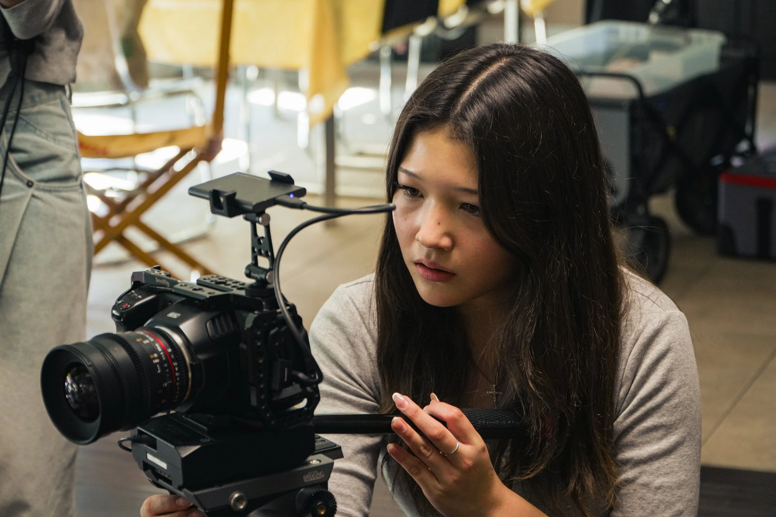 Filmmaker operating a professional cinema camera on a shoulder rig indoors