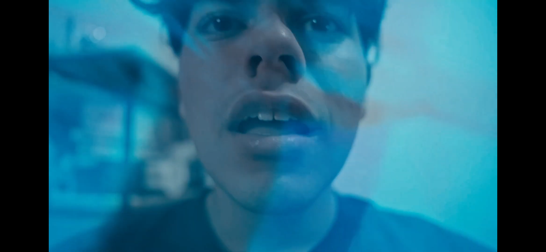 Close-up of a person’s face seen through blue-tinted glass