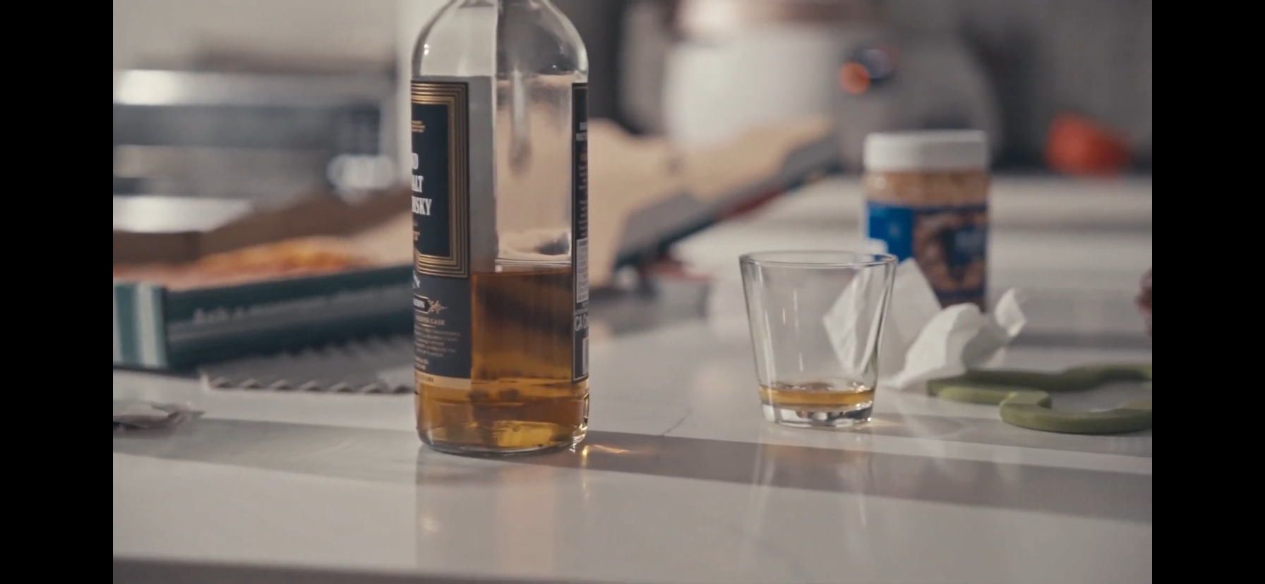 Bottle of whiskey and a partially filled tumbler on a kitchen counter