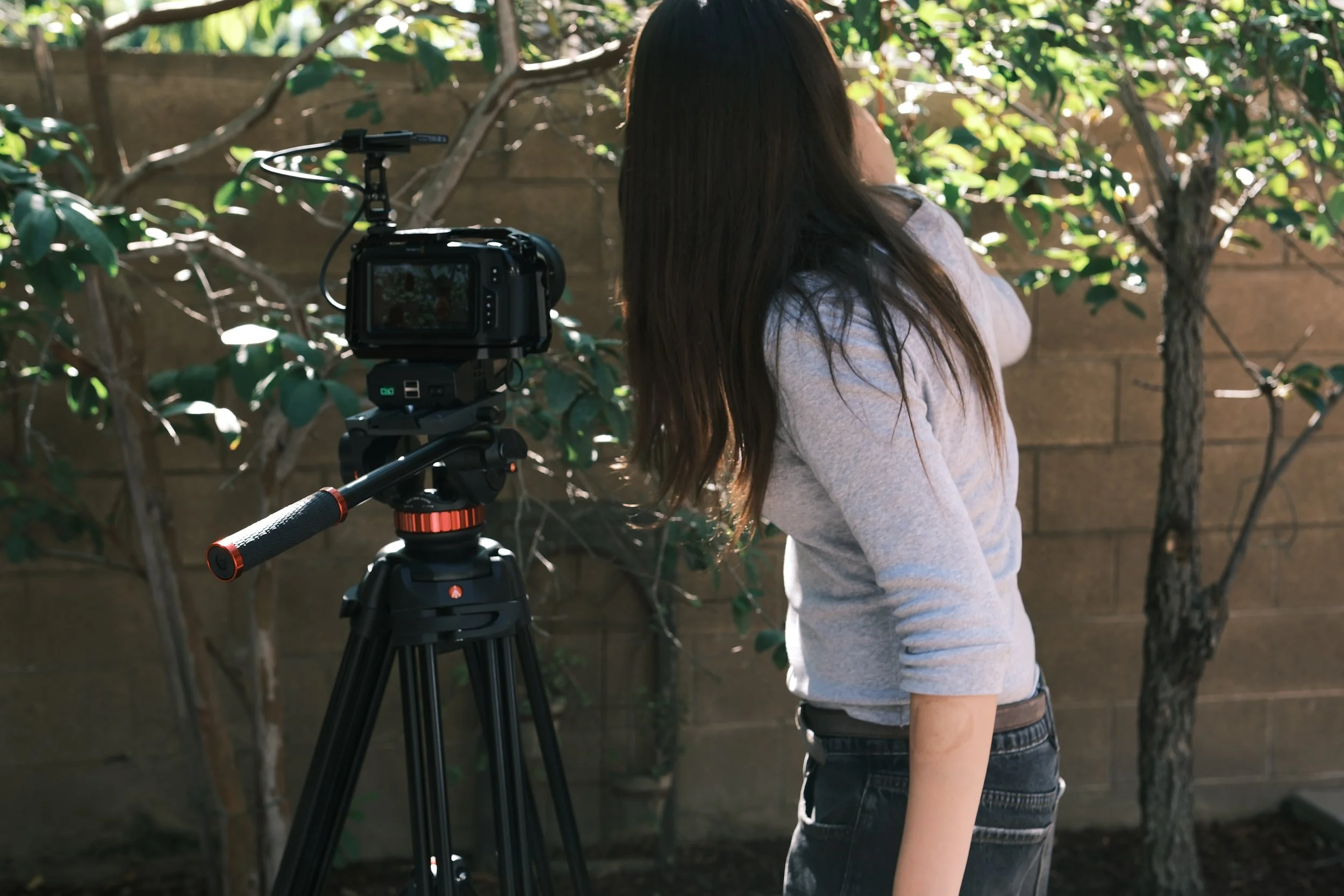 Woman filming outdoors with a professional camera mounted on a tripod