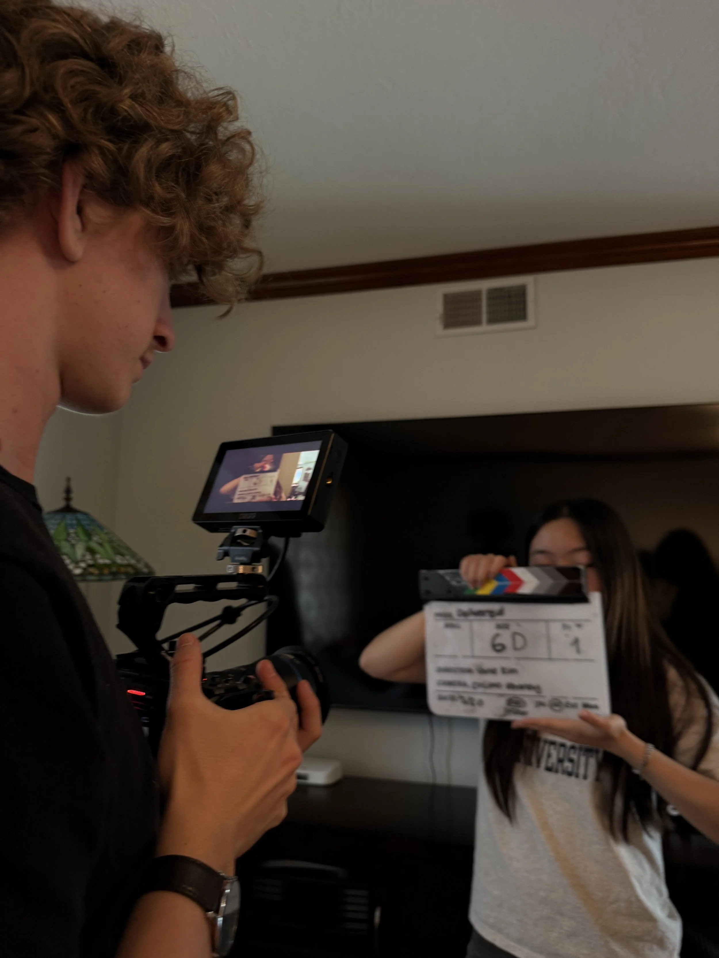Film crew filming a woman holding a movie clapperboard in an indoor studio