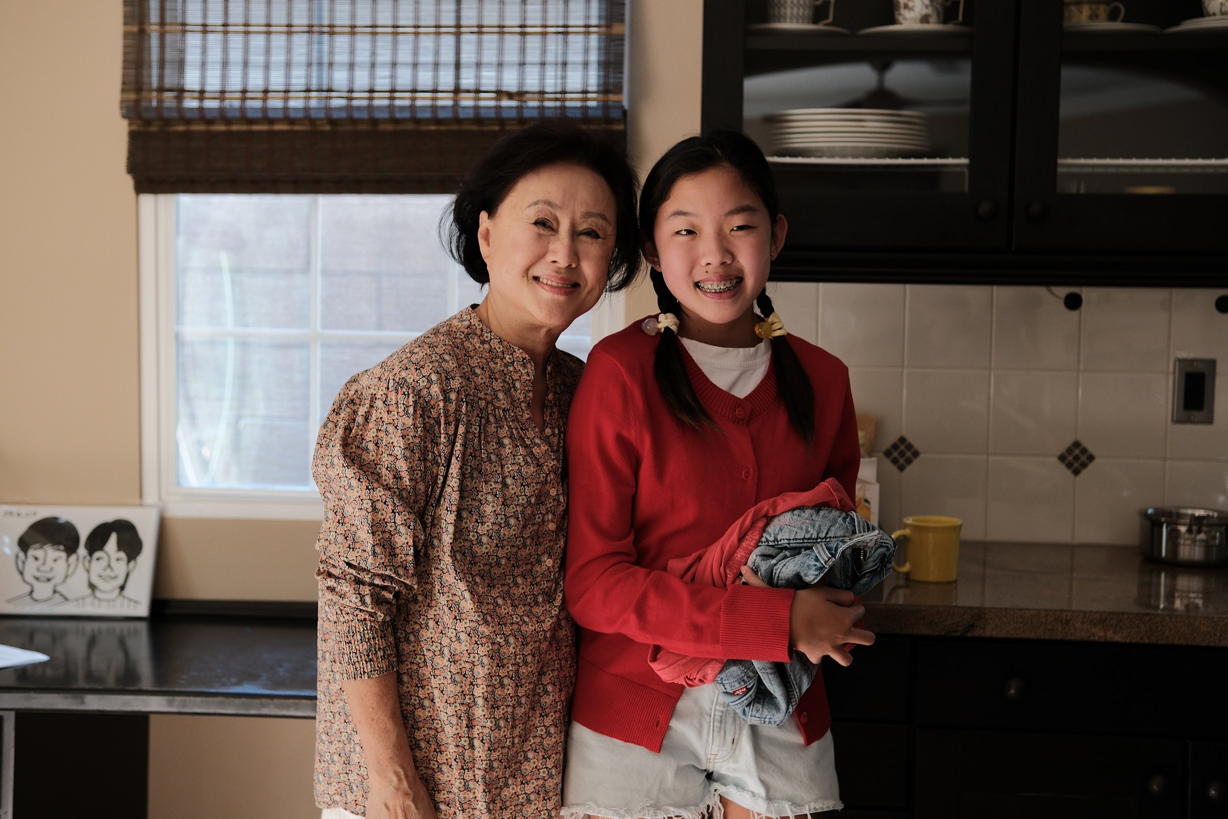 Smiling older woman and teenage girl posing together in a home kitchen