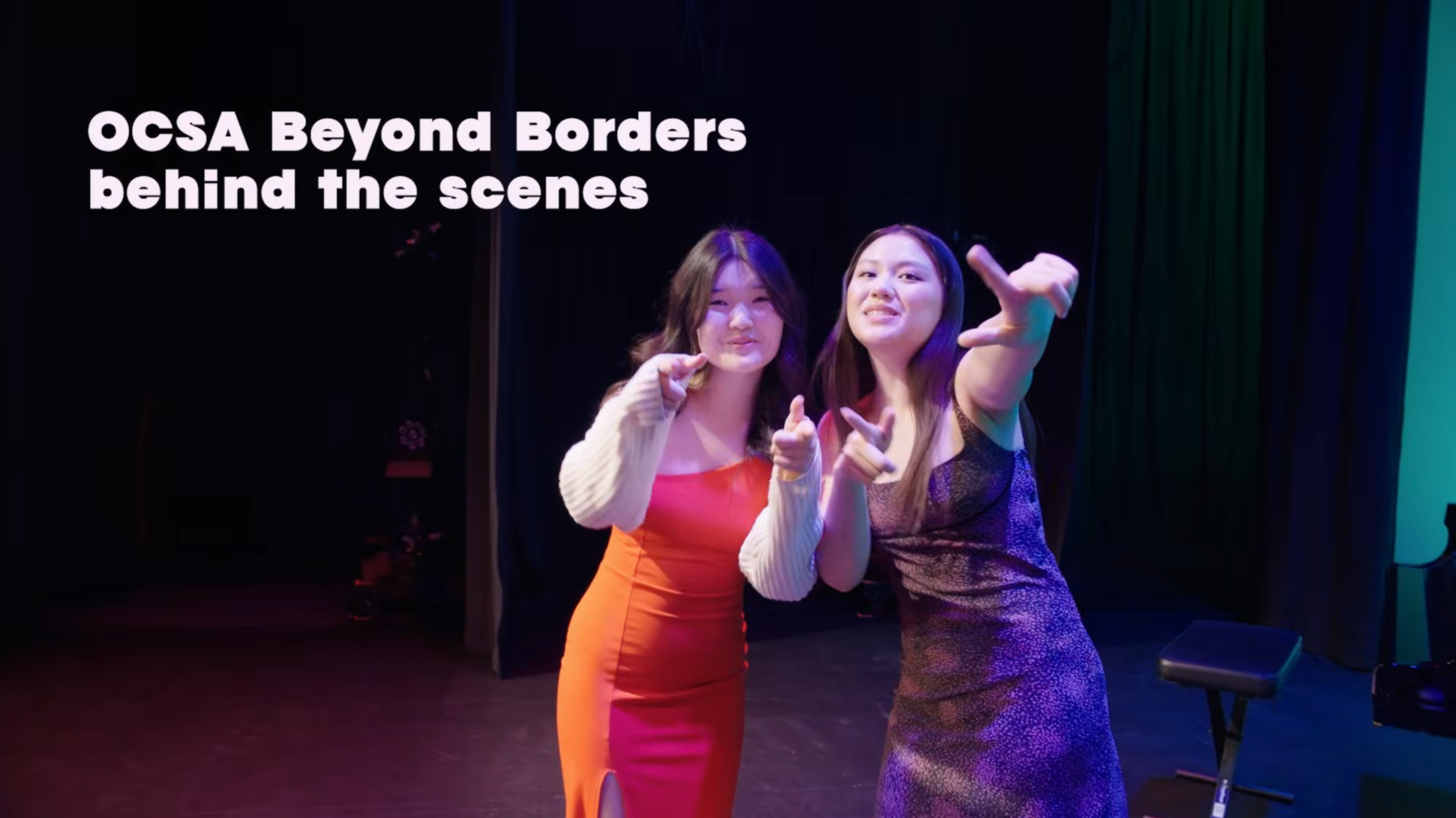 Two women pose backstage on a theater stage under colorful lighting, with text reading “OCSA Beyond Borders behind the scenes.”