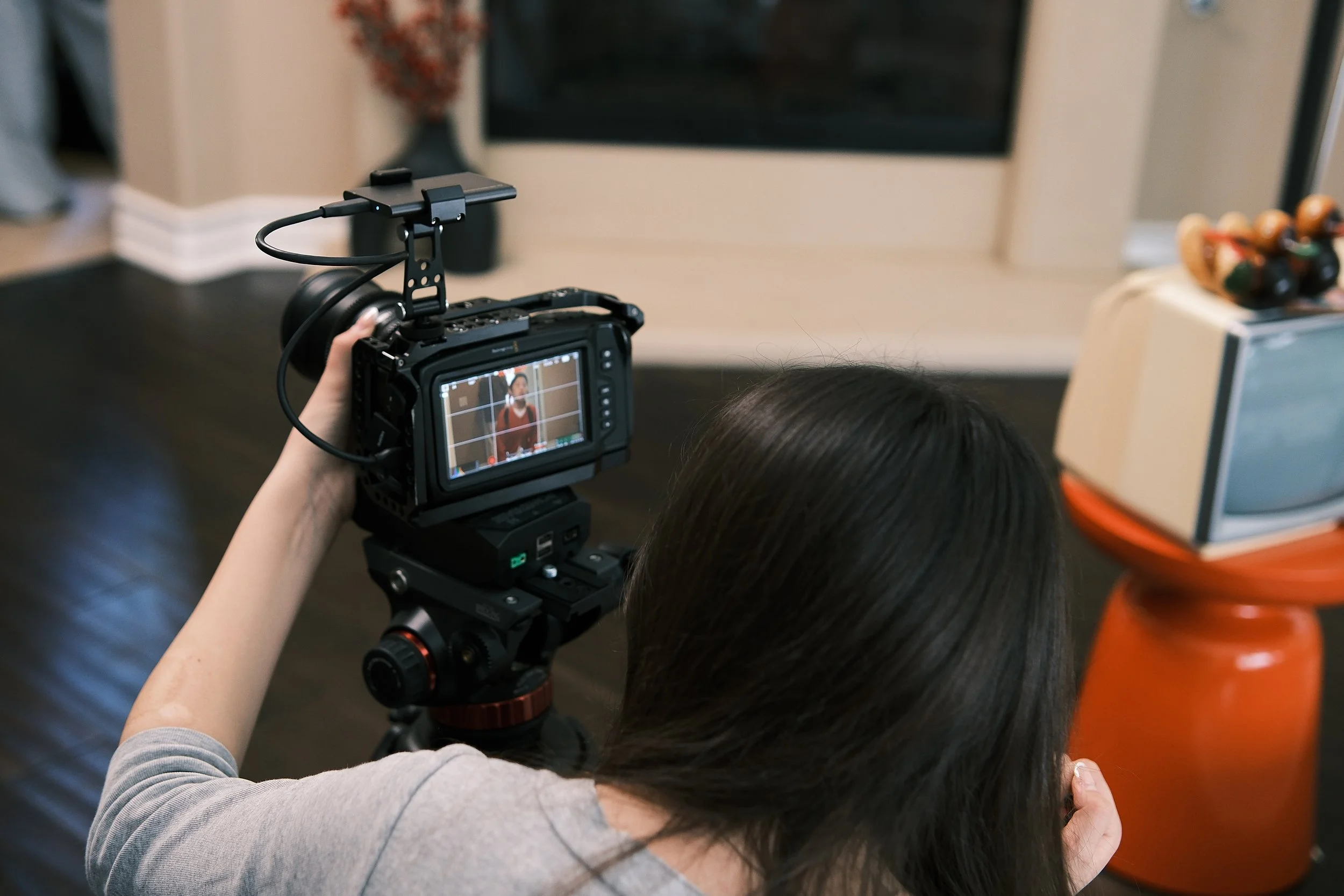 Videographer operating a professional cinema camera with an external monitor indoors