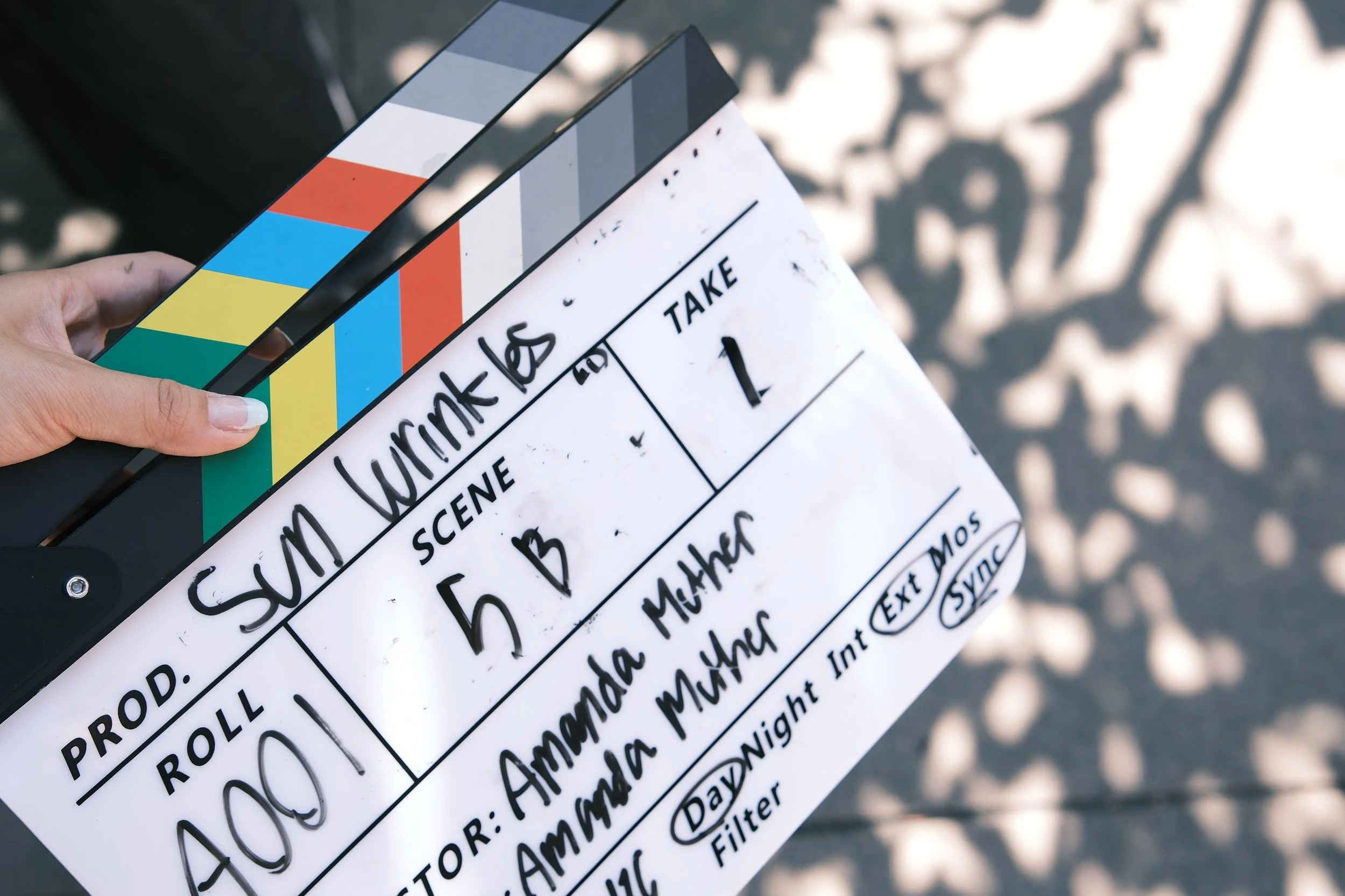 Close-up of a hand holding a film clapperboard and colorful slate outdoors