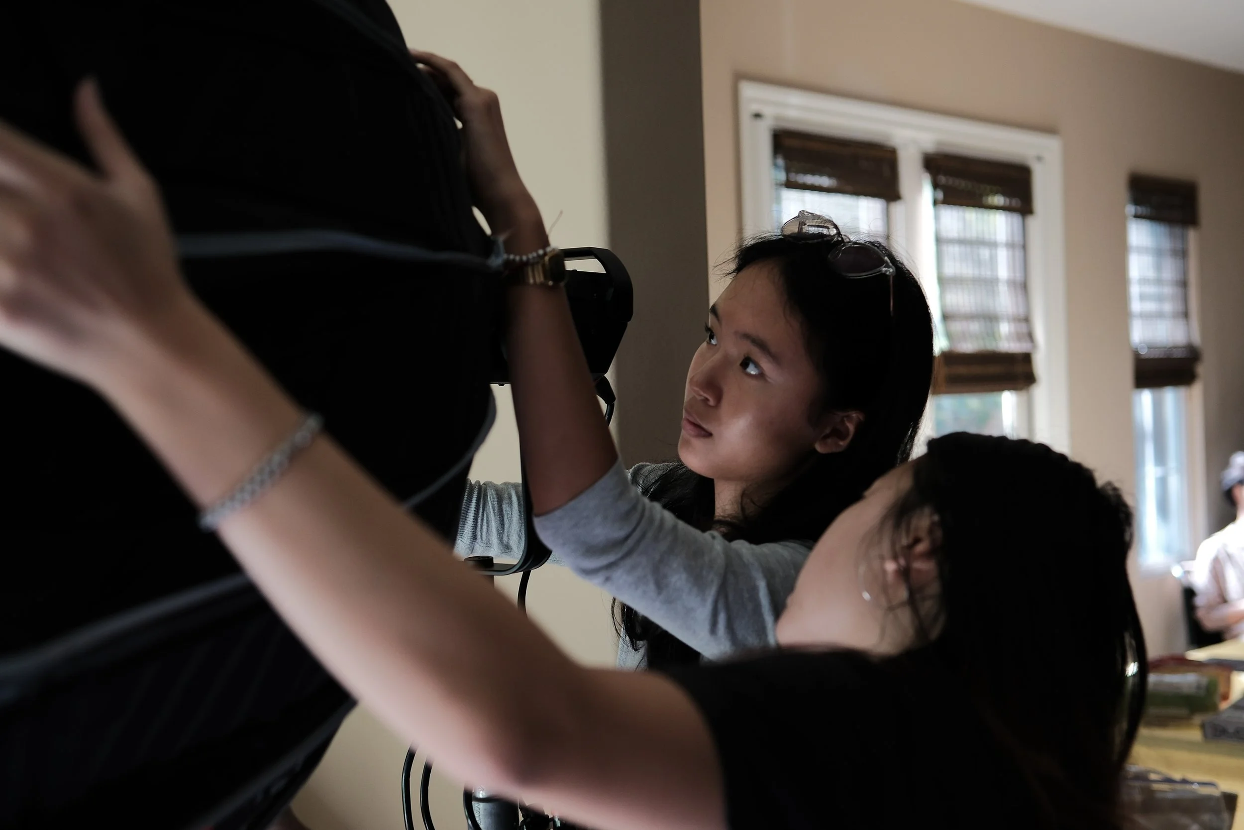 Film crew adjusting a camera rig indoors while a woman looks on