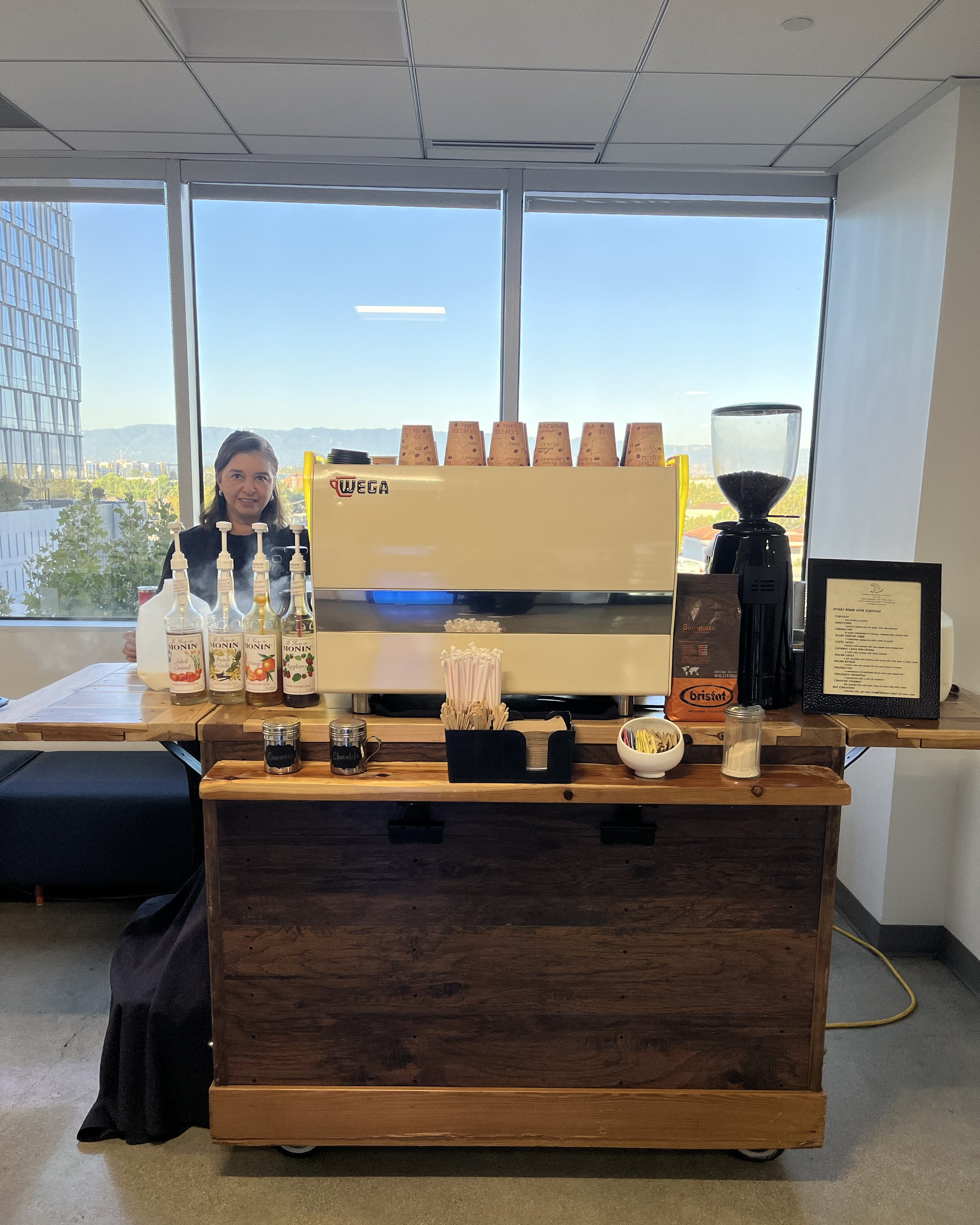 MyEspresso Founder at a fully equipped specialty coffee catering station serving a corporate office in Silicon Valley — professional espresso bar setup with grinder, syrups, and branded supplies