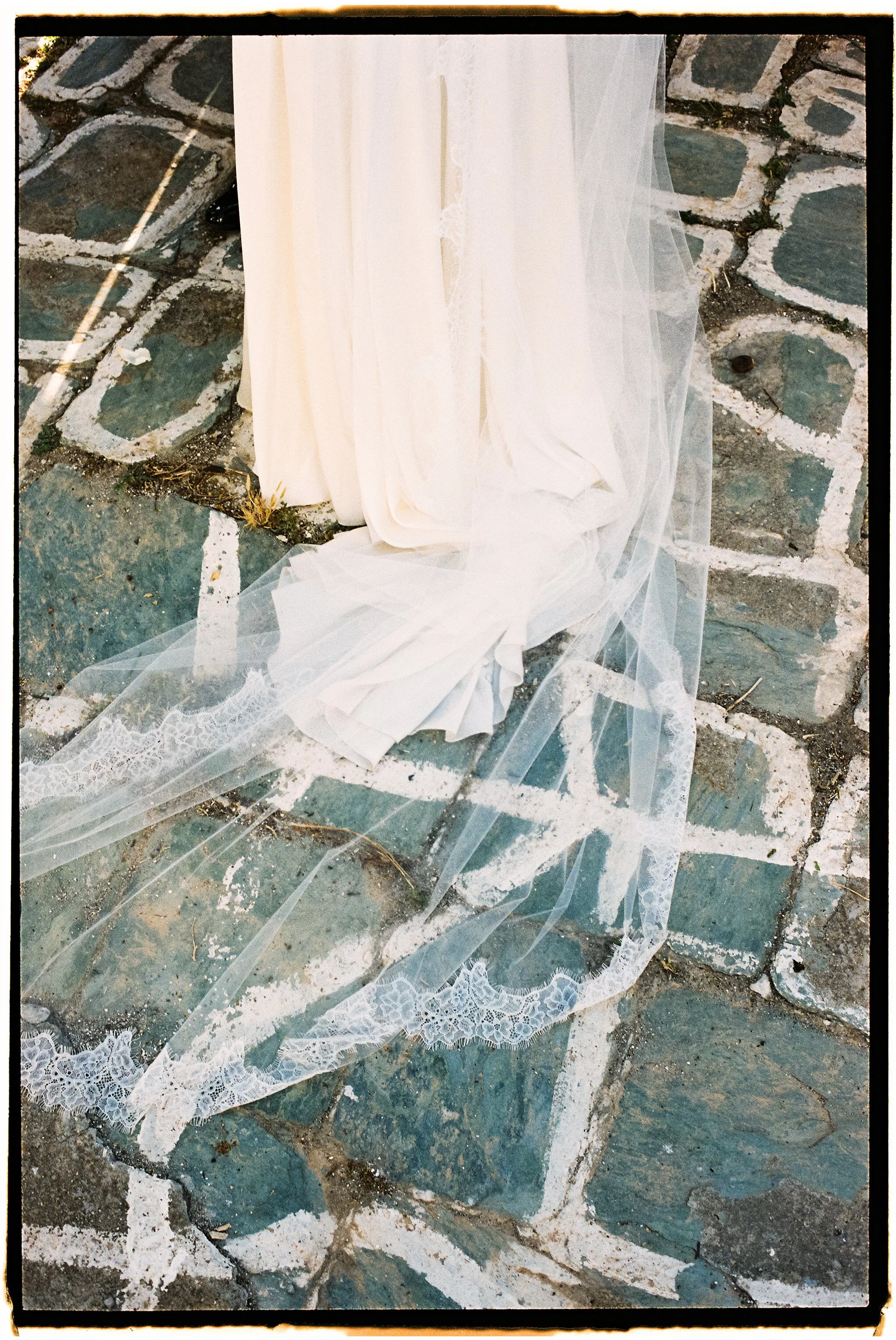 A white veil and fabric lying on a cobblestone ground.