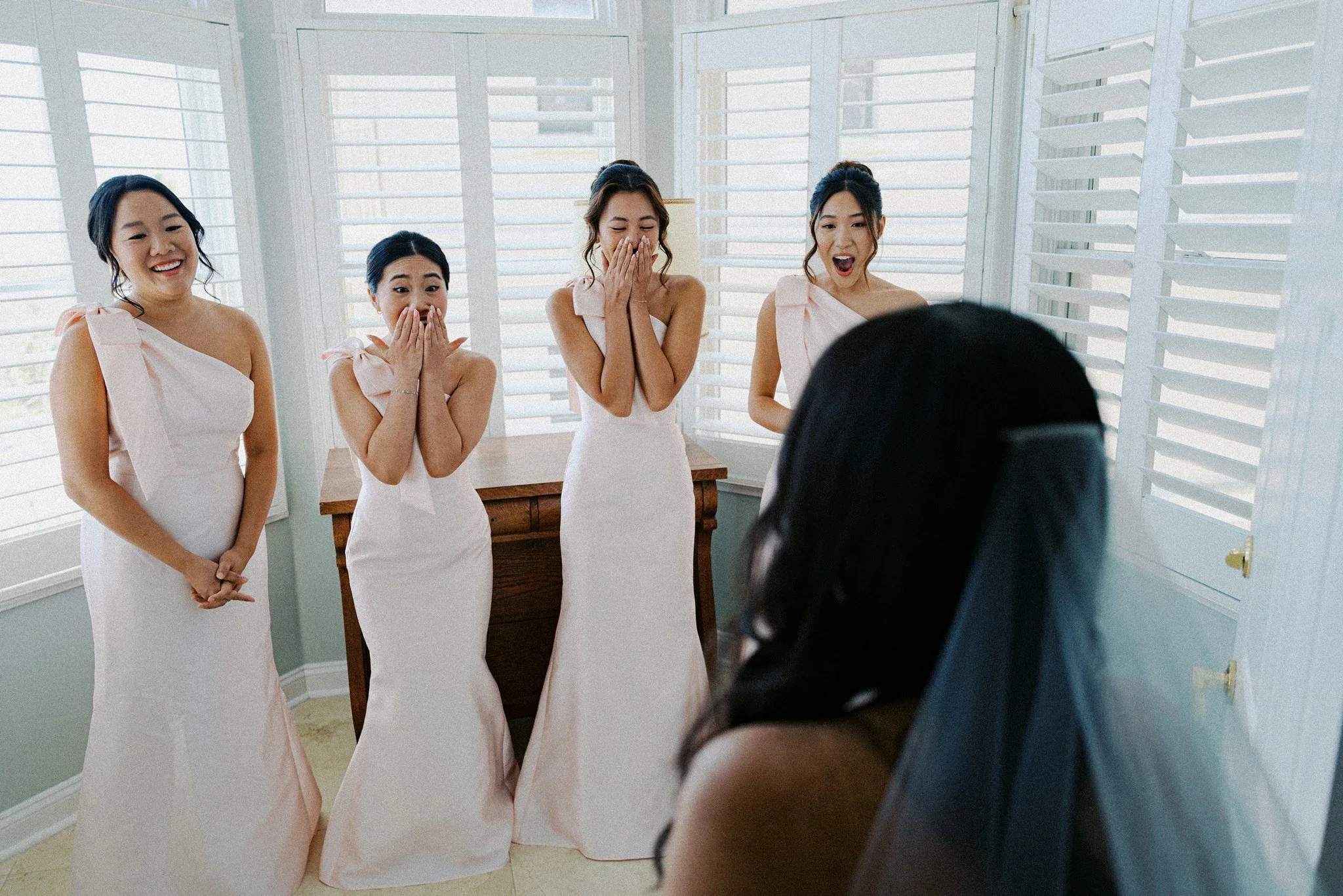 the bridesmaids crying on their first look with the bride in her wedding dress