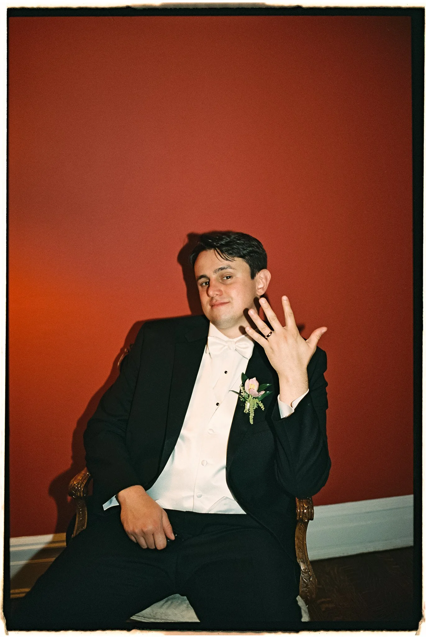 a groom holding up his wedding ring in an editorial film flash photo