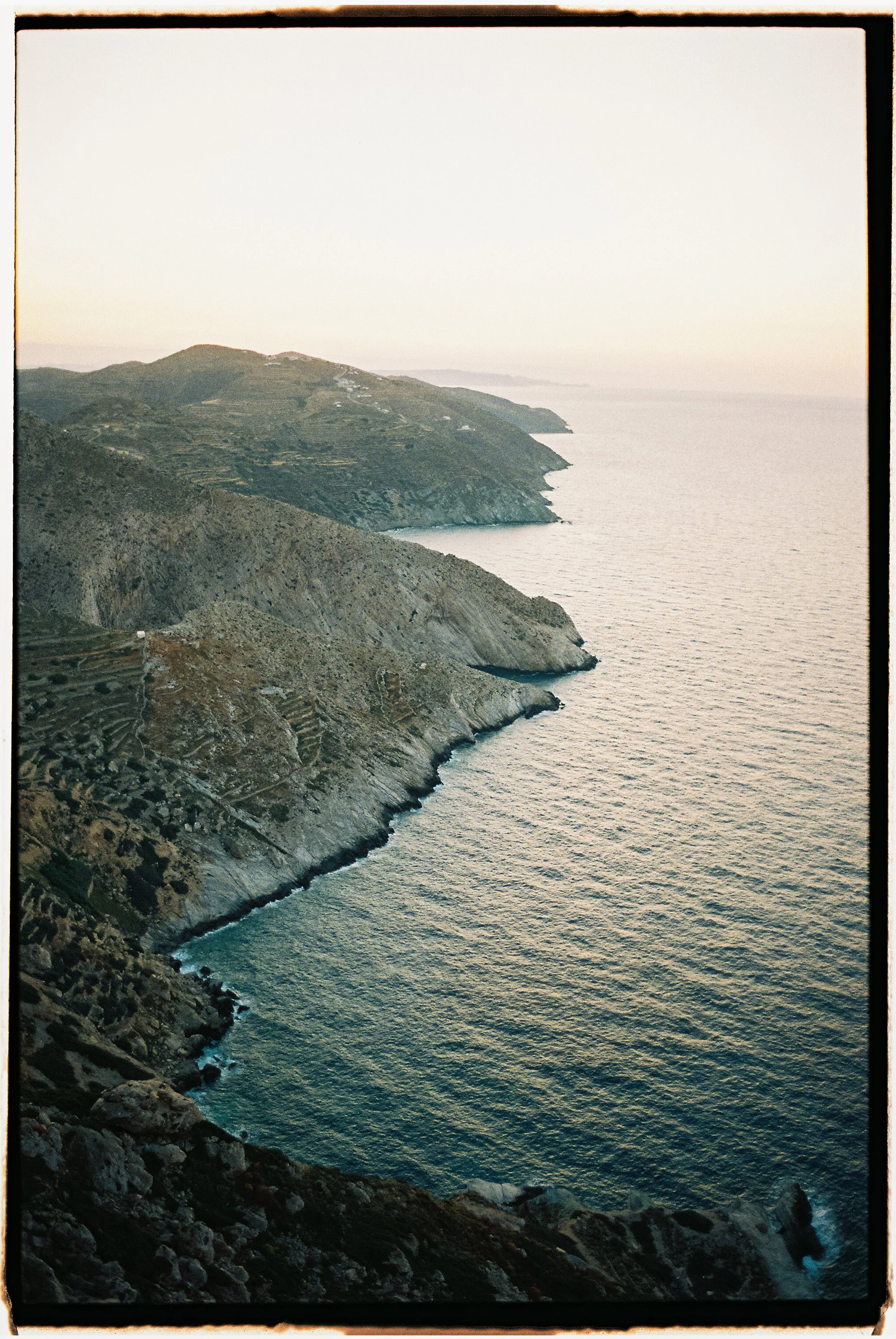 Cliffs along a coastline with rocky terrain, overlooking the ocean during sunset or sunrise.