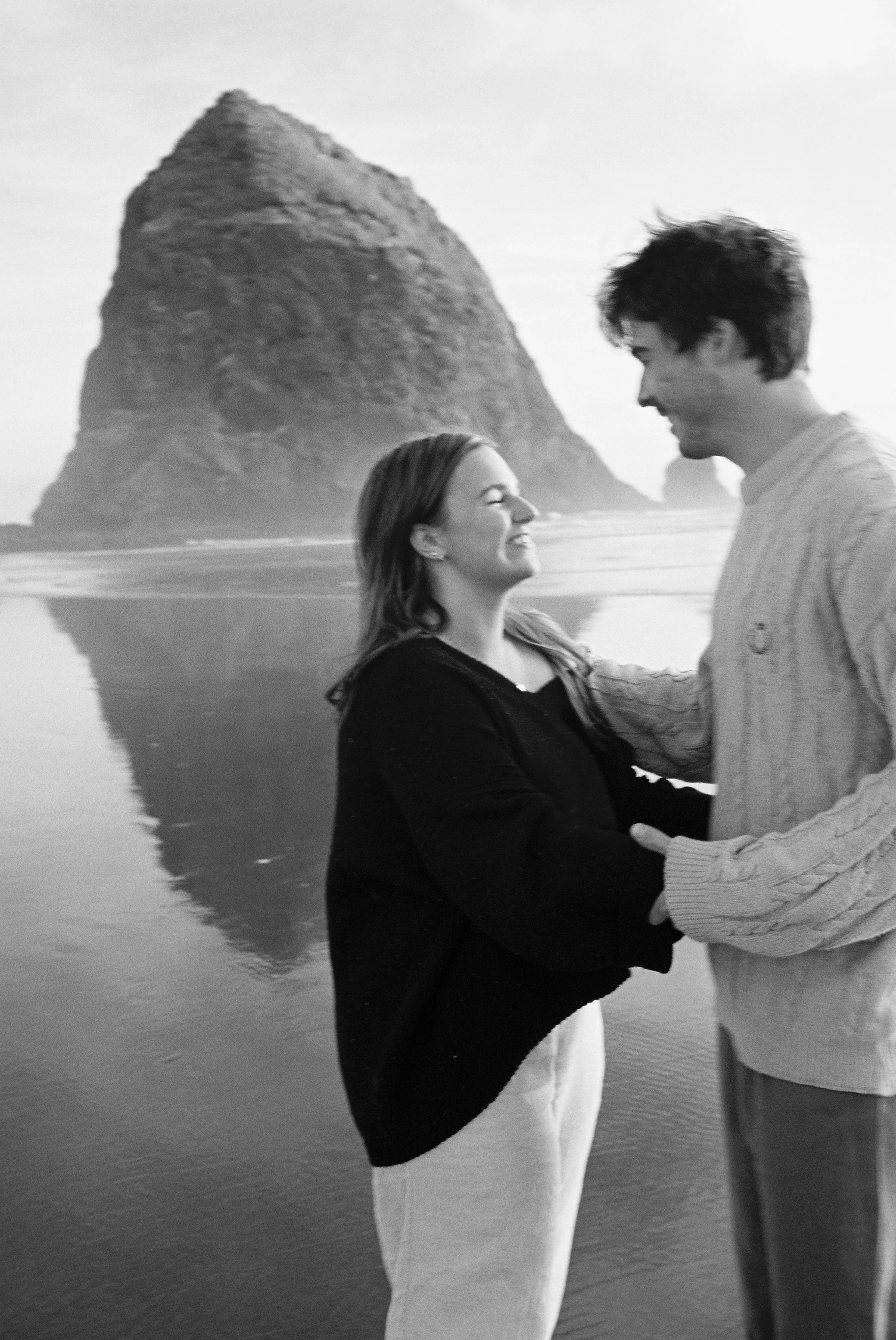 a couple laughing near haystack rock in cannon beach