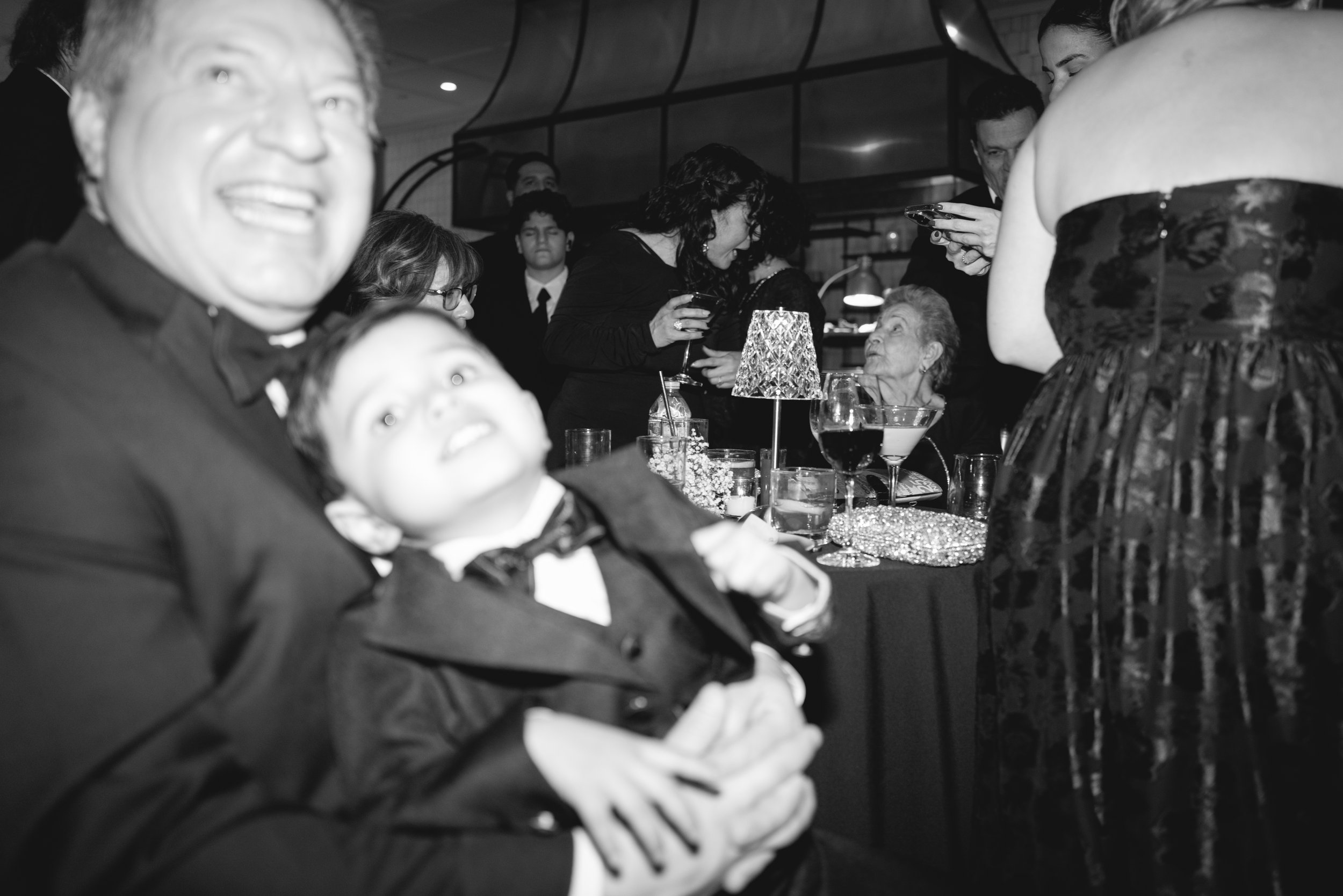 A black-and-white photo of a crowded party or gathering with people socializing around a table.