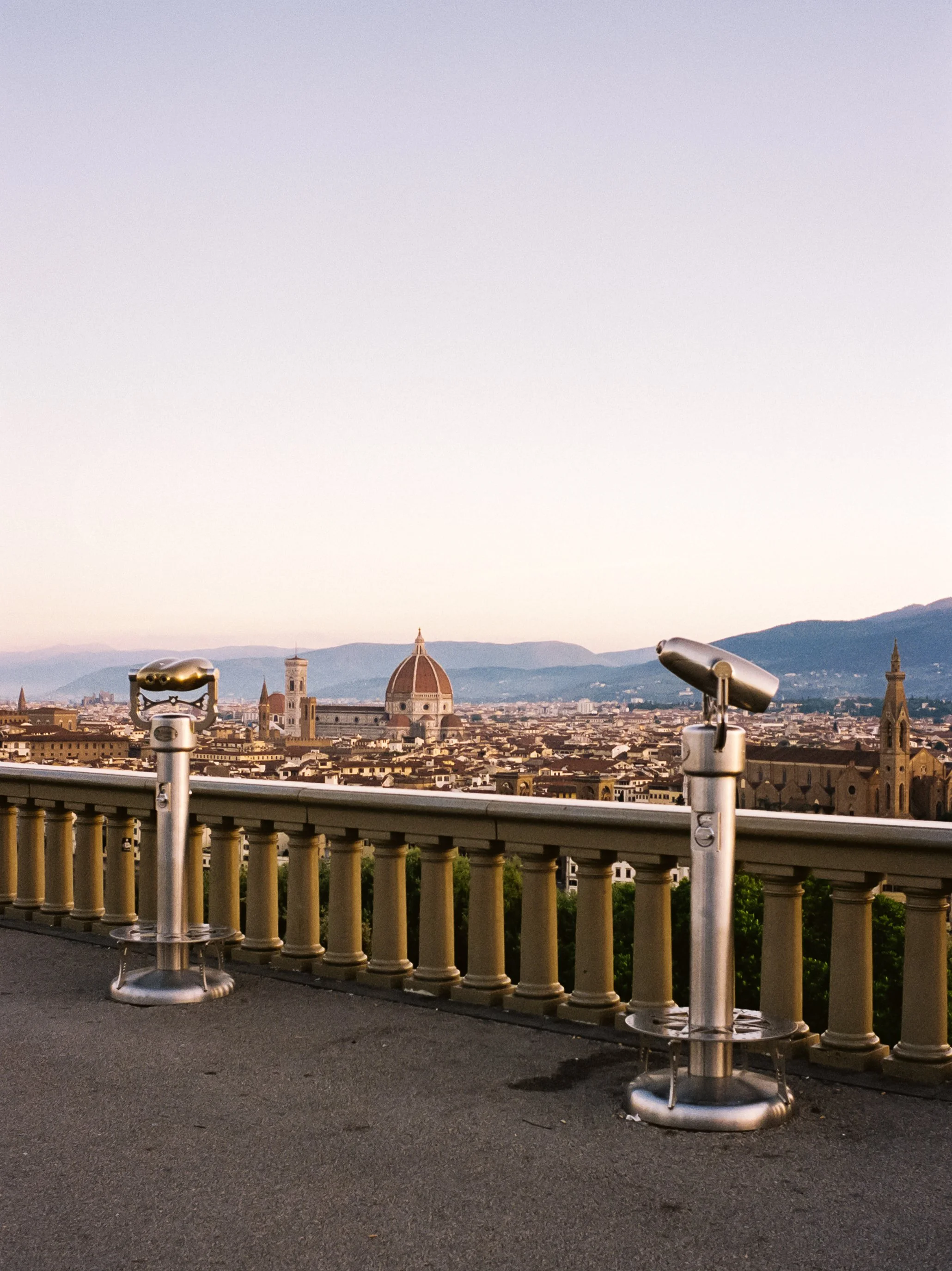 View of Florence, Italy skyline with the Florence Cathedral and surrounding buildings, seen from a lookout with coin-operated binoculars in the foreground.