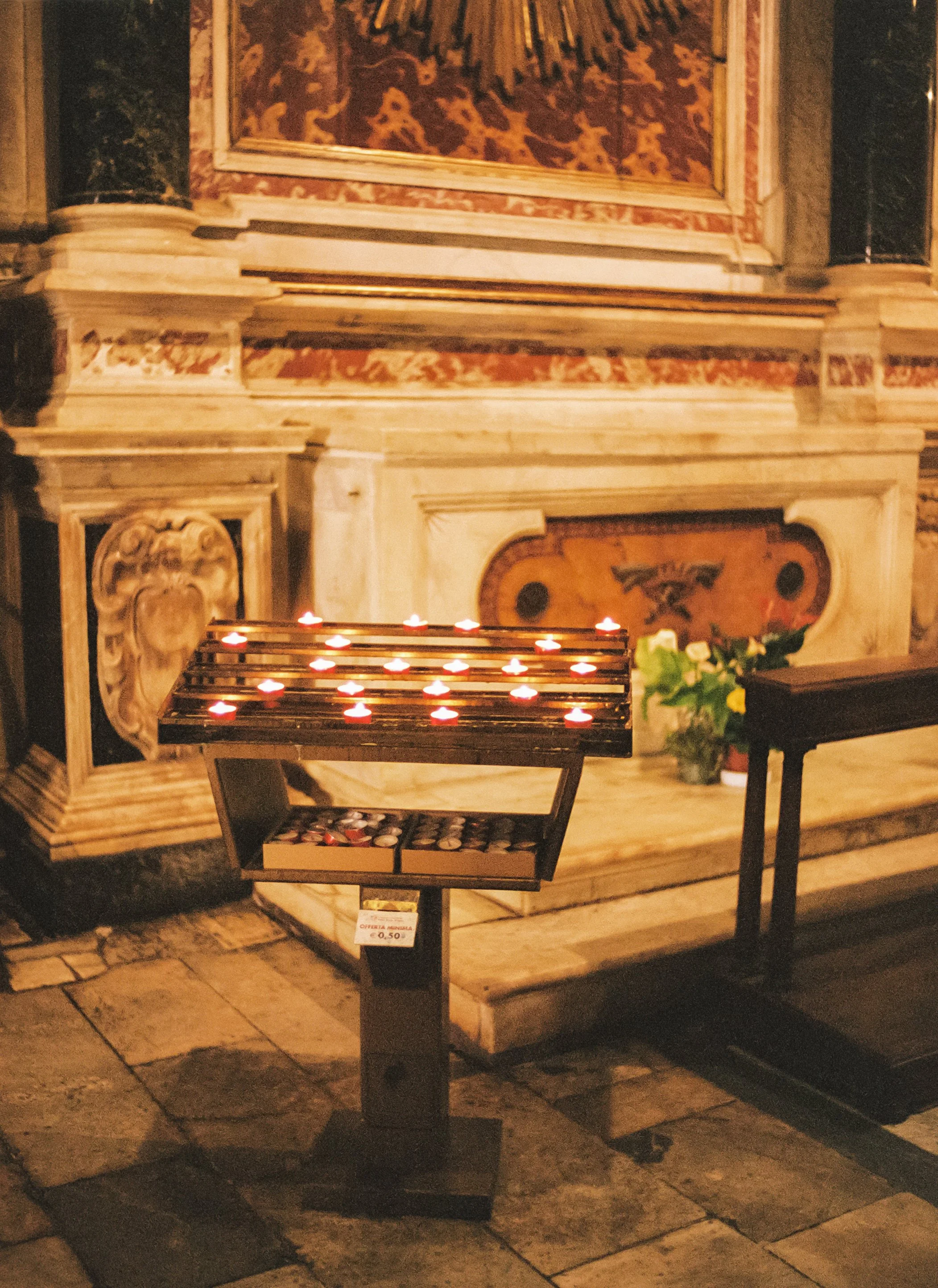 A display with small lit candles in a dark church or chapel.